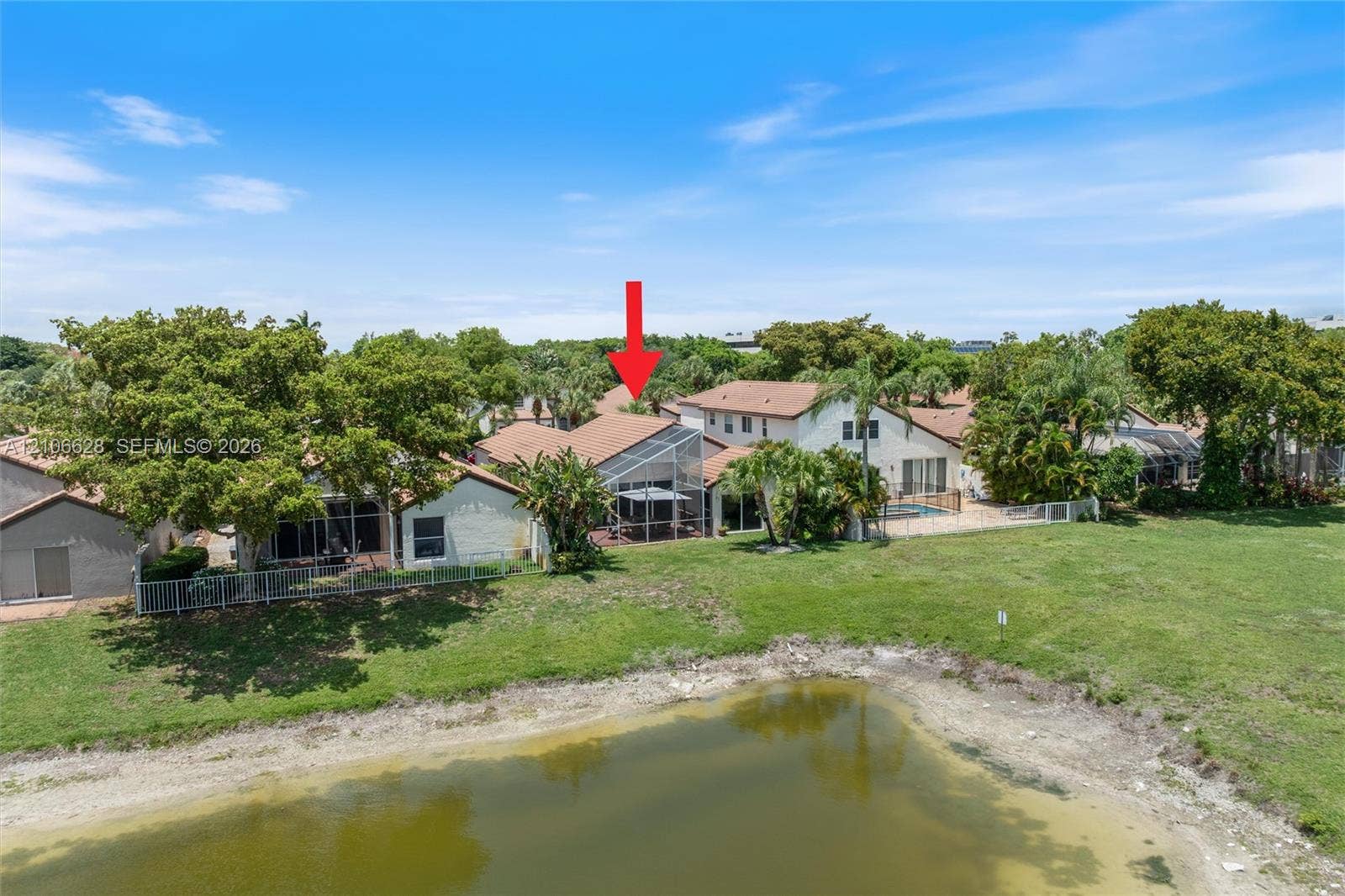 7259 Via Palomar, Boca Raton, FL 33433 Aerial perspective of a multi-family property featuring a screened-in lanai, tile roof, pond frontage, and mature landscaping