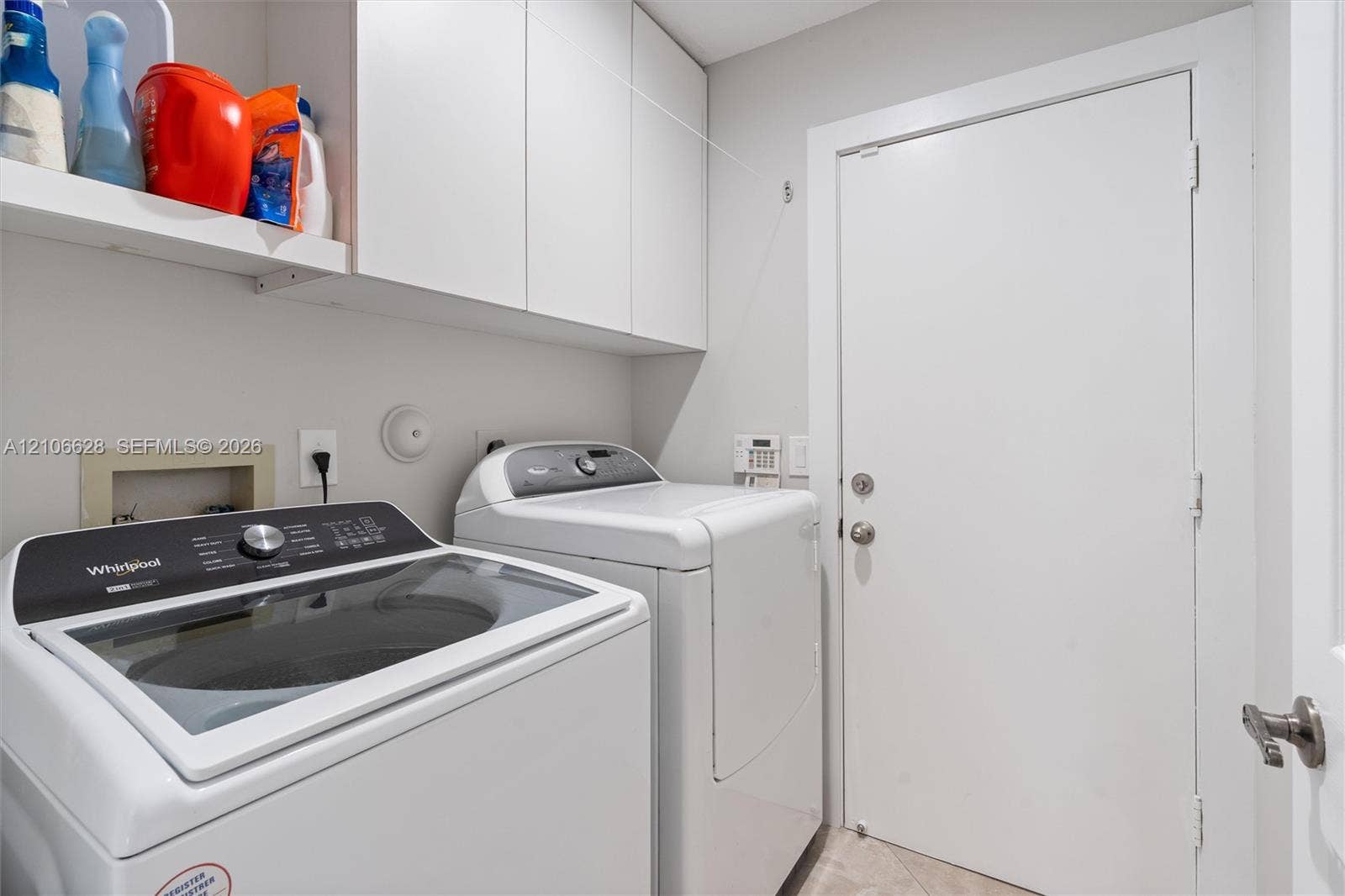 7259 Via Palomar, Boca Raton, FL 33433 Laundry area featuring white flat-panel upper cabinetry, an open built-in shelf, and a solid-core door with satin nickel hardware