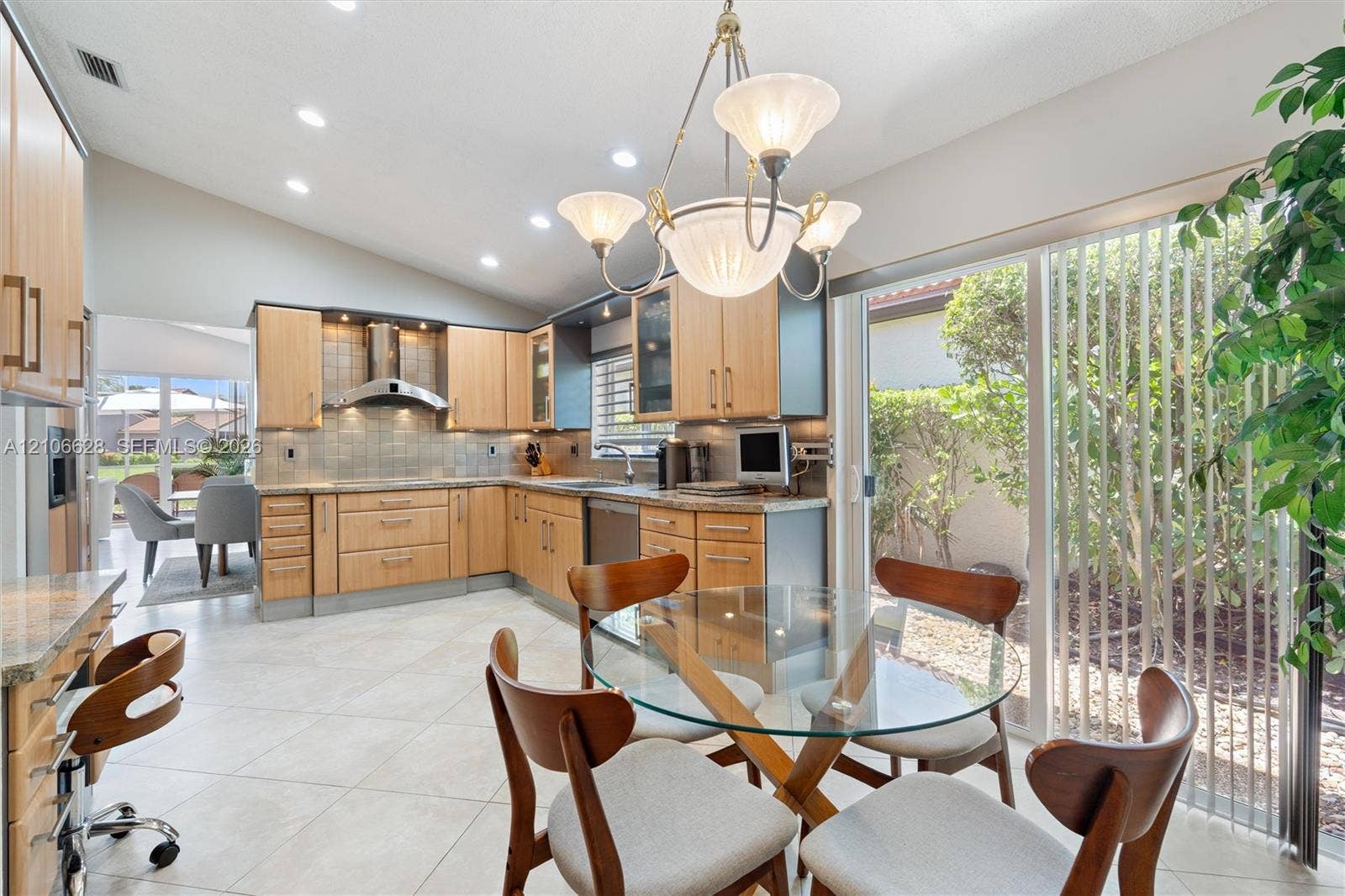 7259 Via Palomar, Boca Raton, FL 33433 Kitchen featuring wood cabinetry, stone countertops, stainless steel range hood, recessed lighting, and large sliding glass doors