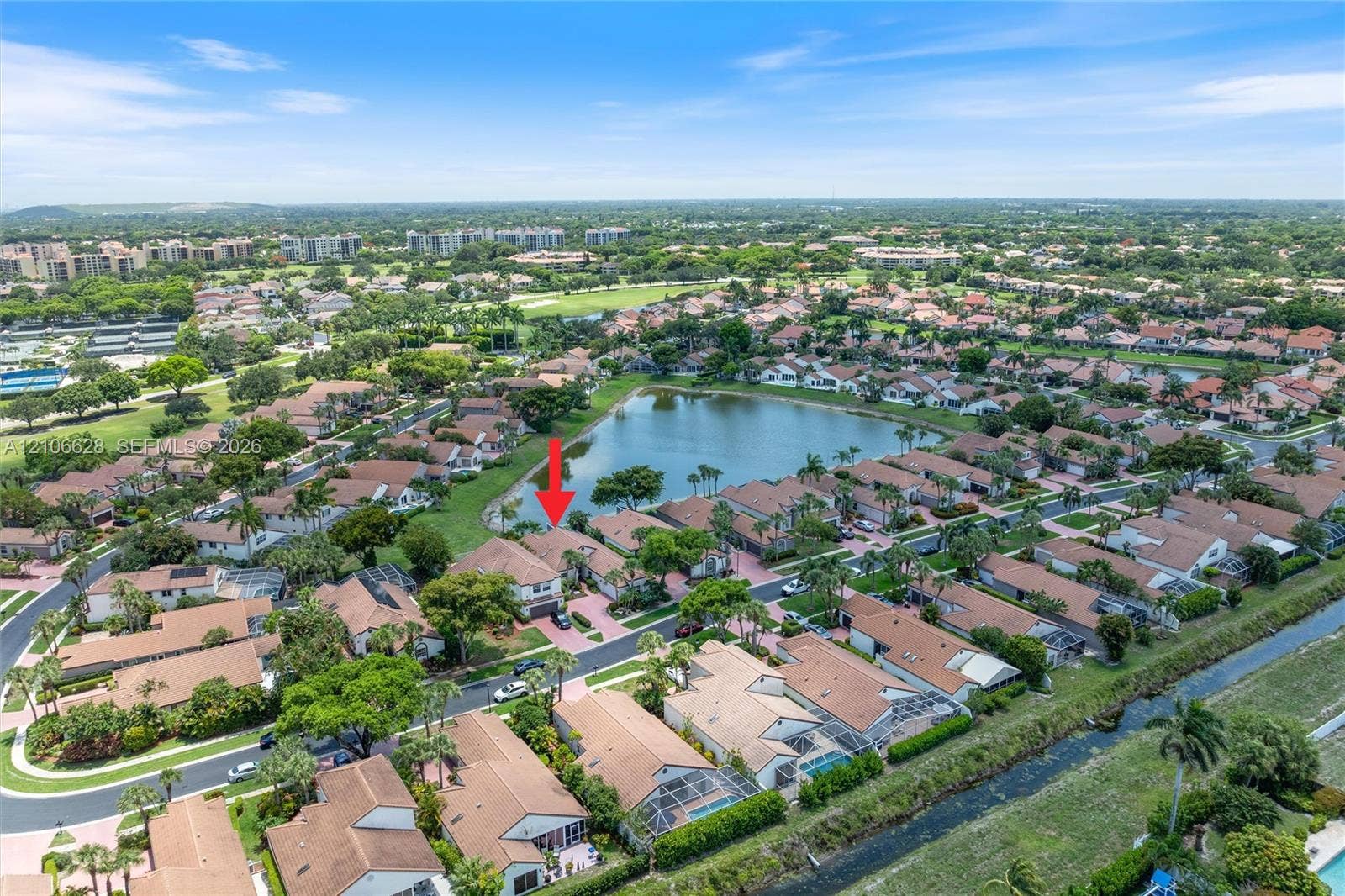 7259 Via Palomar, Boca Raton, FL 33433 Aerial perspective of a multi-story residence featuring a paved driveway, tile roof, and waterfront location within a residential community