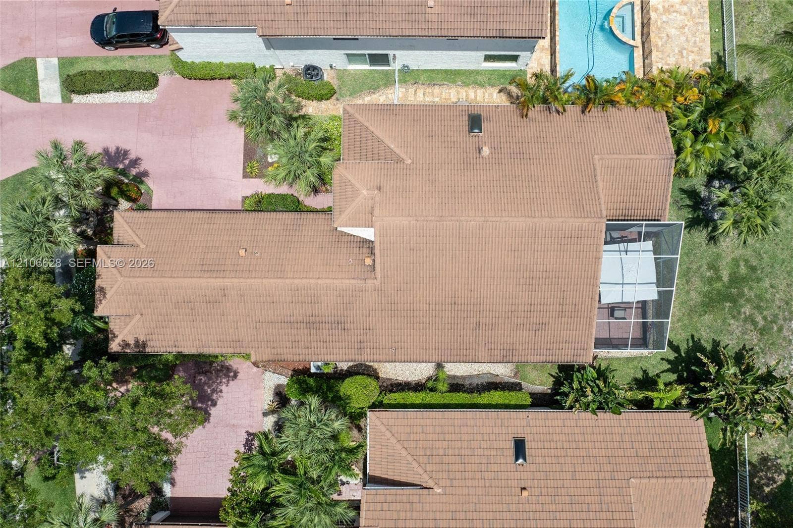 7259 Via Palomar, Boca Raton, FL 33433 Aerial perspective featuring a tile roof, an in-ground pool with stone-finish decking, and a screened-in lanai