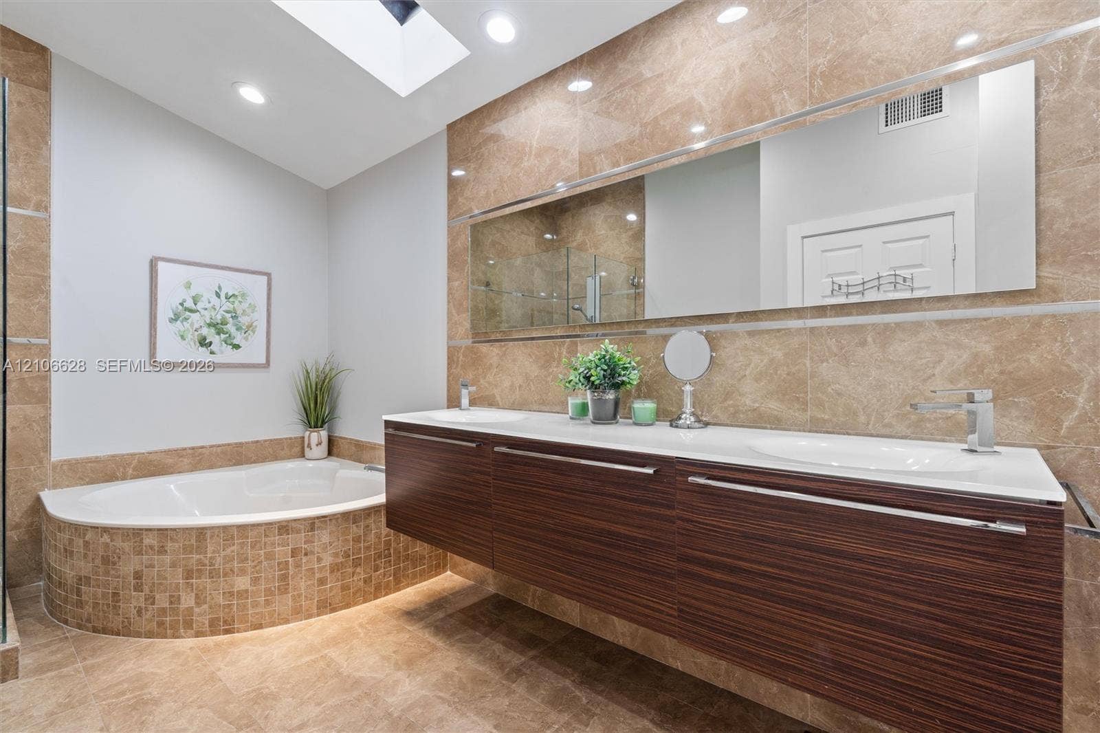 7259 Via Palomar, Boca Raton, FL 33433 Floating vanity with dual-integrated sinks, wood-finish cabinetry, full-width wall mirror, oversized soaking tub with mosaic tile surround, and skylight