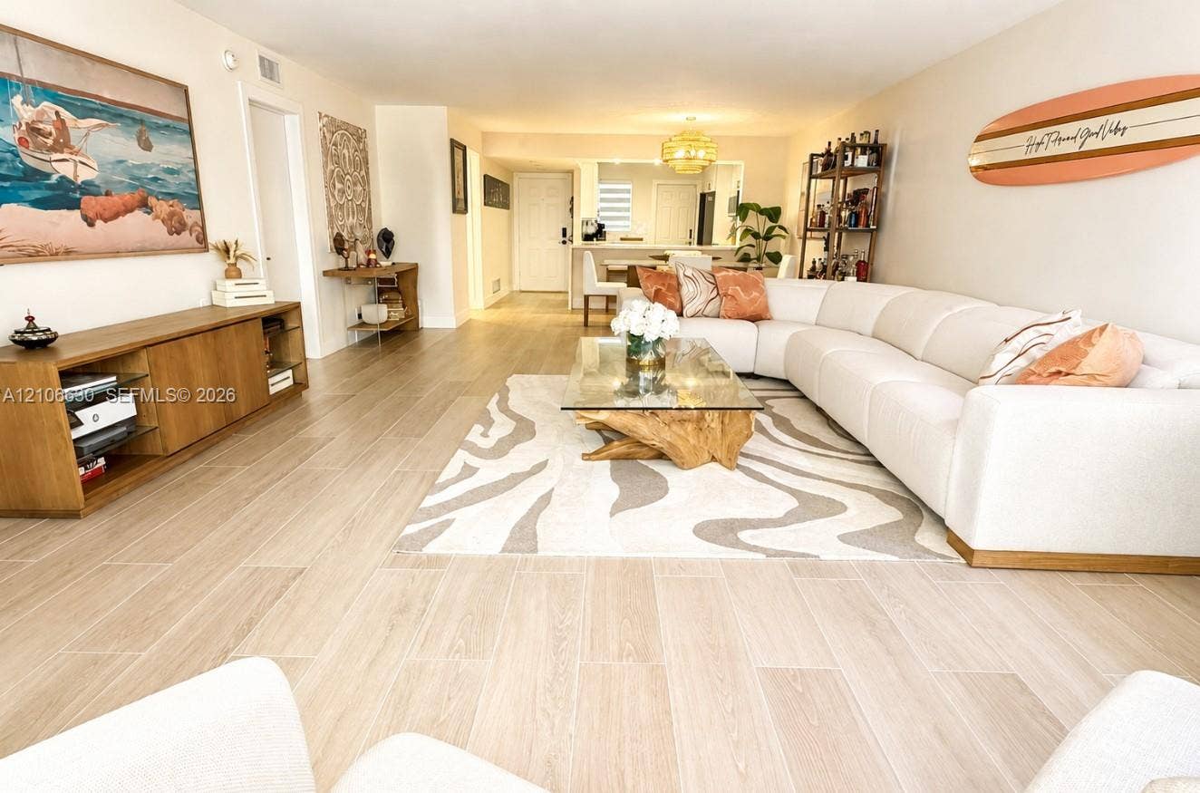 Open-concept interior featuring wood-finish flooring, a kitchen pass-through window, and a built-in recessed ceiling light fixture