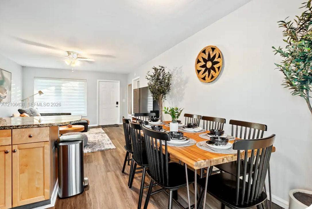 Open-concept interior featuring light wood-finish flooring, wood cabinetry with stone-finish countertops, and a ceiling fan