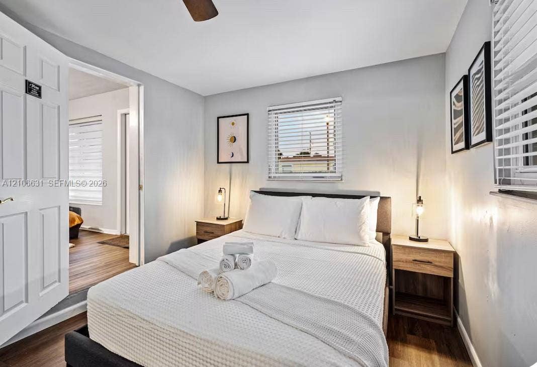 Bedroom featuring wood-finish flooring, a ceiling fan, and horizontal blinds on dual windows