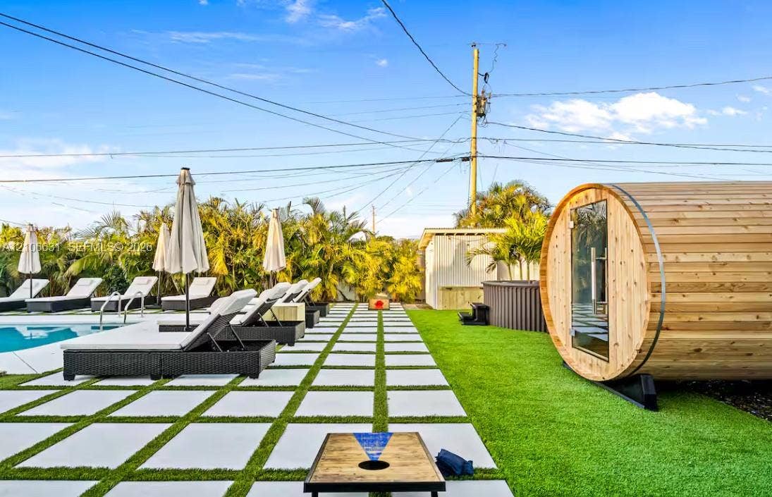 Outdoor living area featuring a swimming pool, cedar barrel sauna, synthetic turf lawn, and large-format paver patio