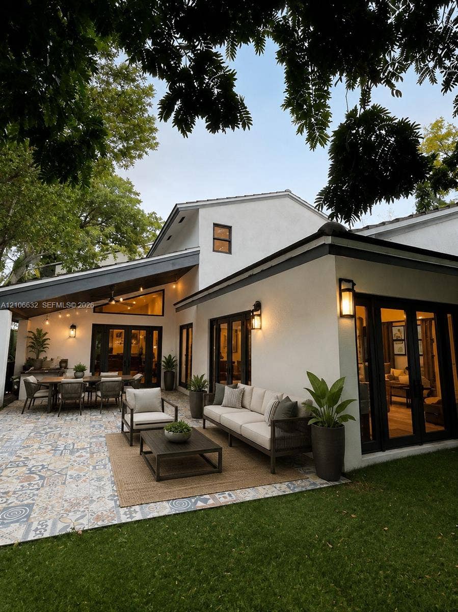 AI enhanced photo. Patio featuring patterned tile flooring, covered architectural overhang, exterior wall-mounted lighting, and double glass-paned doors