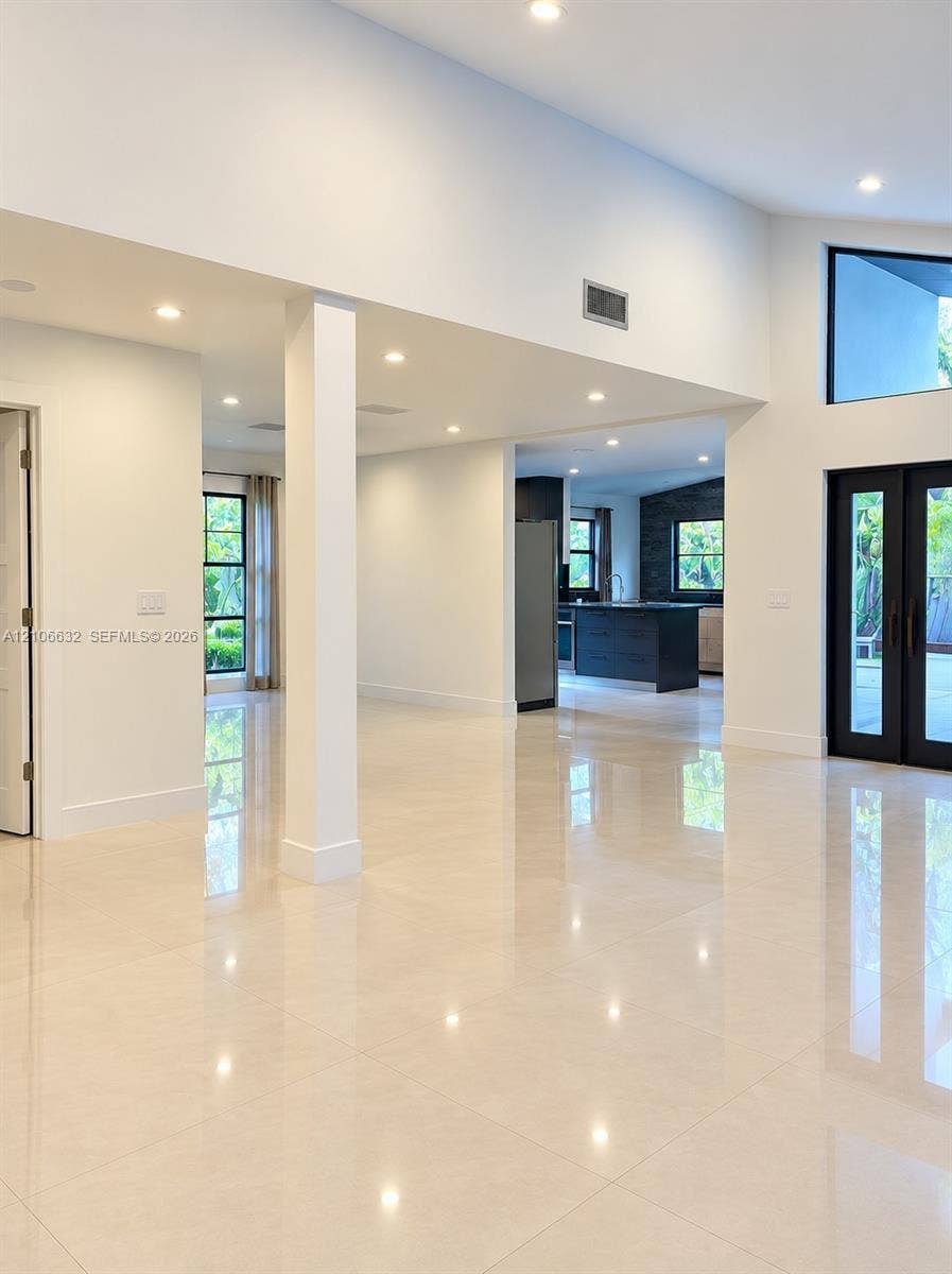 Open interior featuring large-format tile flooring, vaulted ceilings, recessed lighting, access to the garden & terrace.
