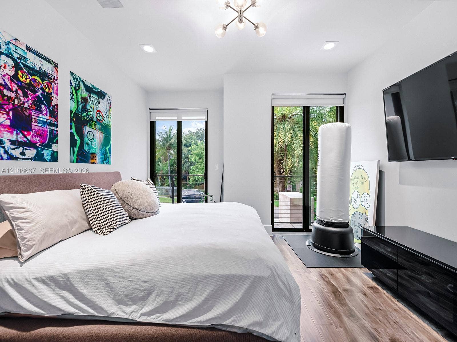 Wood-finish flooring, dual sliding glass doors, recessed lighting, and a multi-arm modern light fixture
