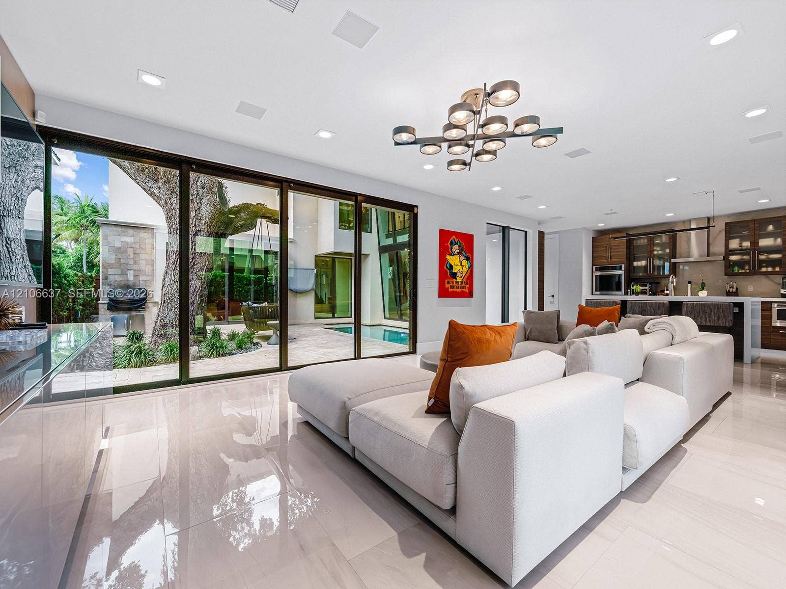 Large-format sliding glass doors, polished porcelain tile flooring, multi-light contemporary chandelier, and recessed ceiling lighting