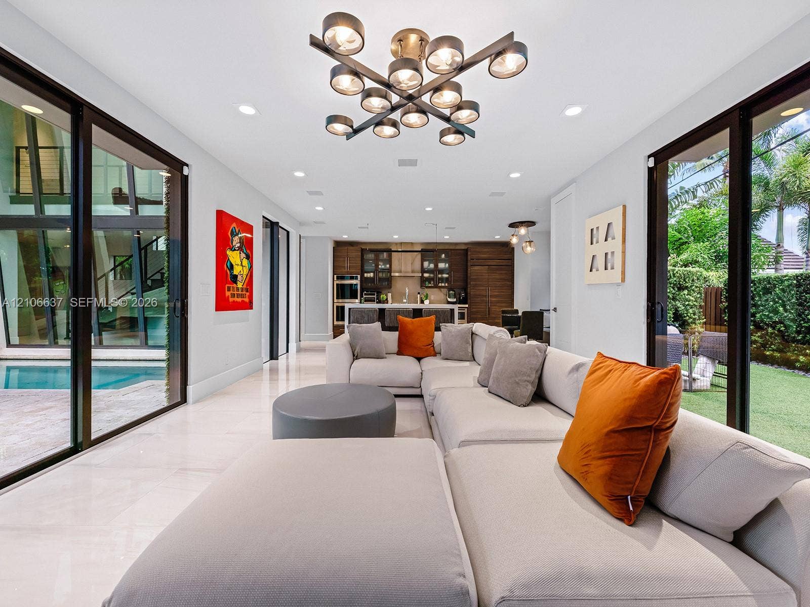 Open-concept interior featuring large-format tile flooring, multi-light geometric chandelier, recessed lighting, and floor-to-ceiling glass sliding doors