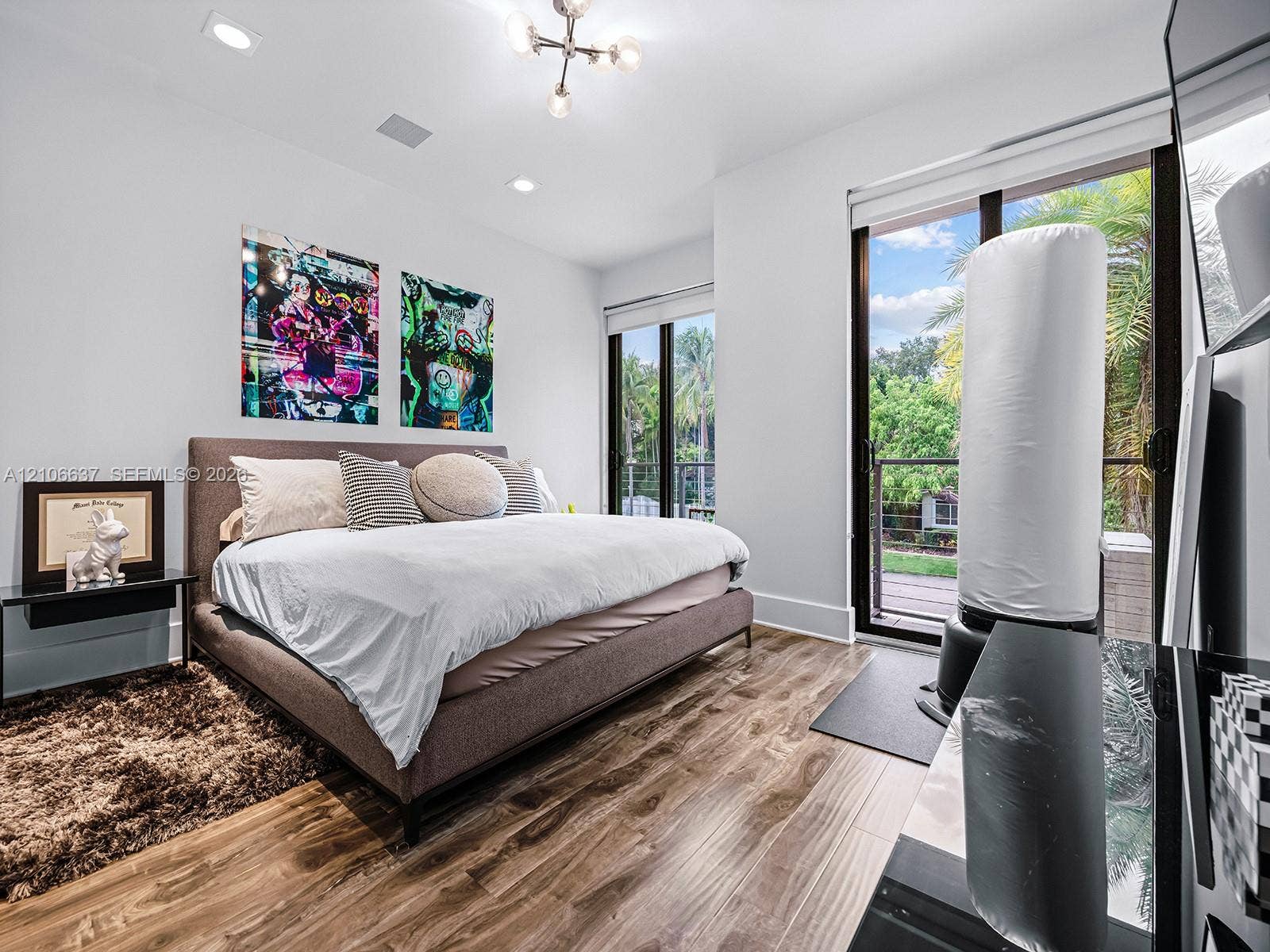 Wood-finish flooring, recessed lighting, modern multi-arm ceiling fixture, and floor-to-ceiling glass sliding doors opening to an outdoor balcony