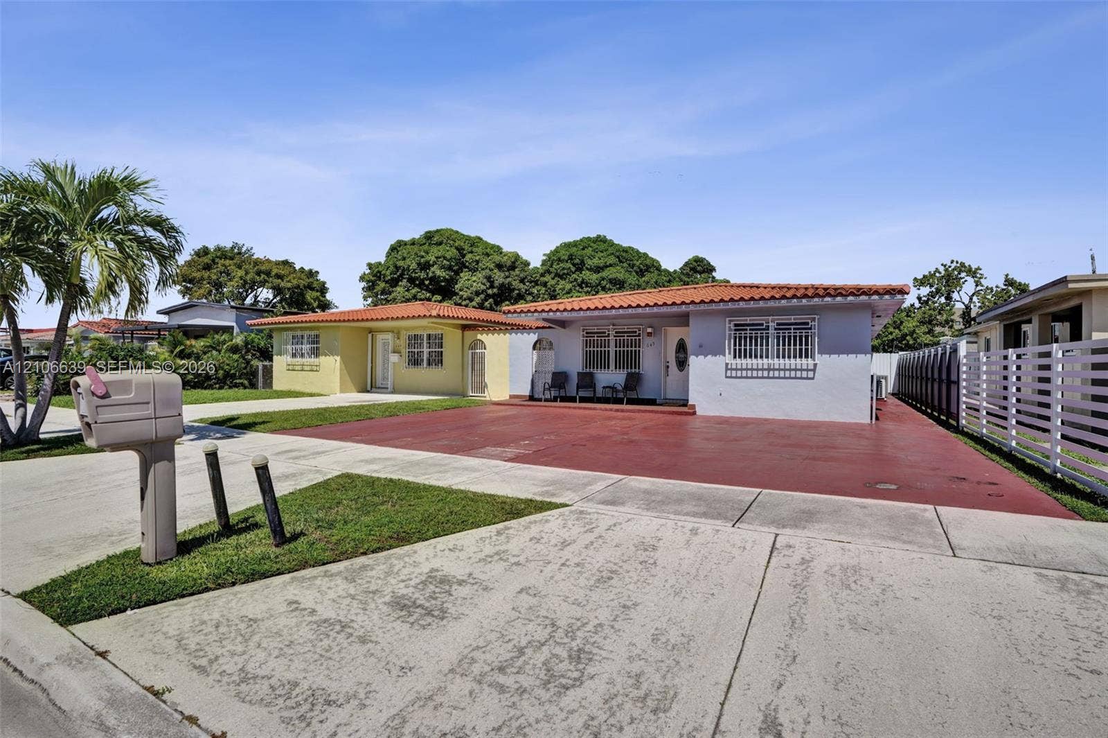 Single-story residence featuring a Mediterranean-style clay tile roof, concrete driveway, and exterior window security bars