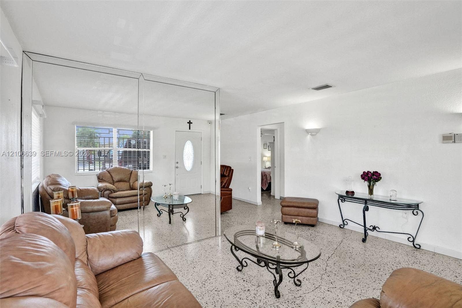 Interior space featuring polished stone-flecked flooring, expansive floor-to-ceiling wall mirrors, and wall-mounted sconce lighting