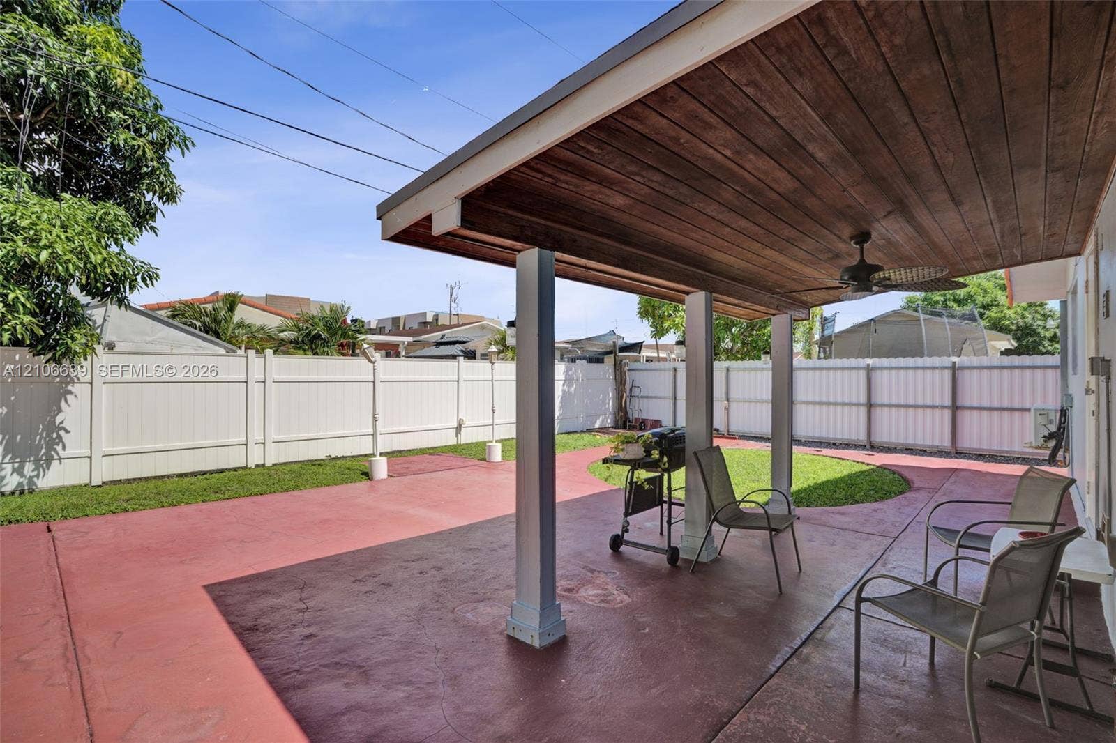 Covered patio featuring a wood-plank ceiling, ceiling fan, stained concrete flooring, and a privacy fence enclosing the backyard