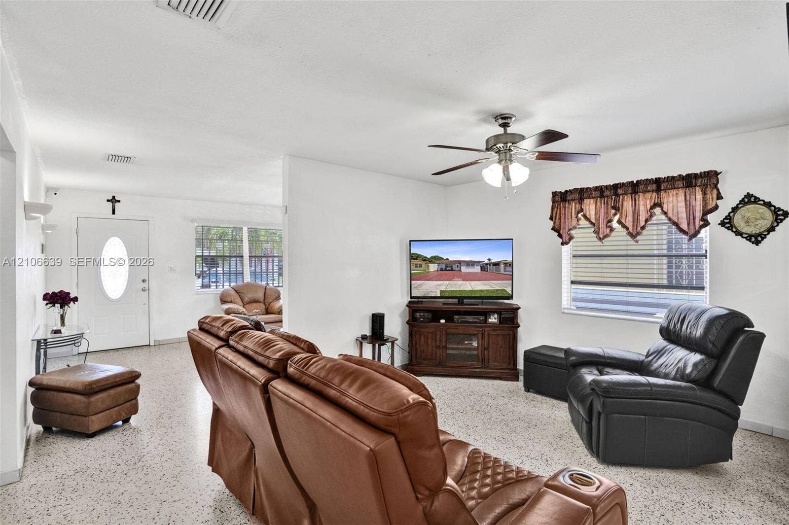 Living area featuring speckled stone-finish flooring, a ceiling fan with integrated lighting, and horizontal sliding windows