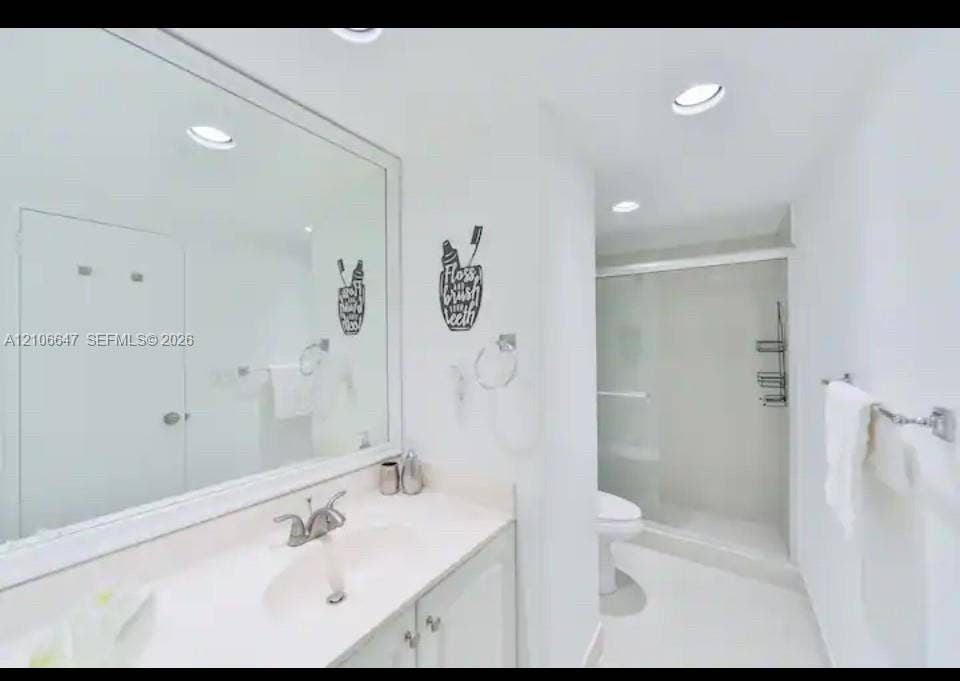 Full-width mirror, vanity with integrated sink, chrome-finished hardware, and walk-in shower enclosure with sliding glass doors