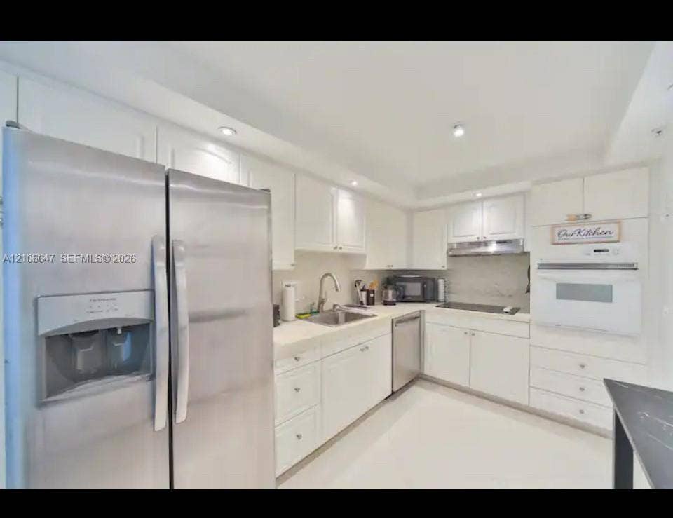 Kitchen featuring white cabinetry, solid-surface countertops, stainless steel appliances, a double-door refrigerator, and recessed lighting