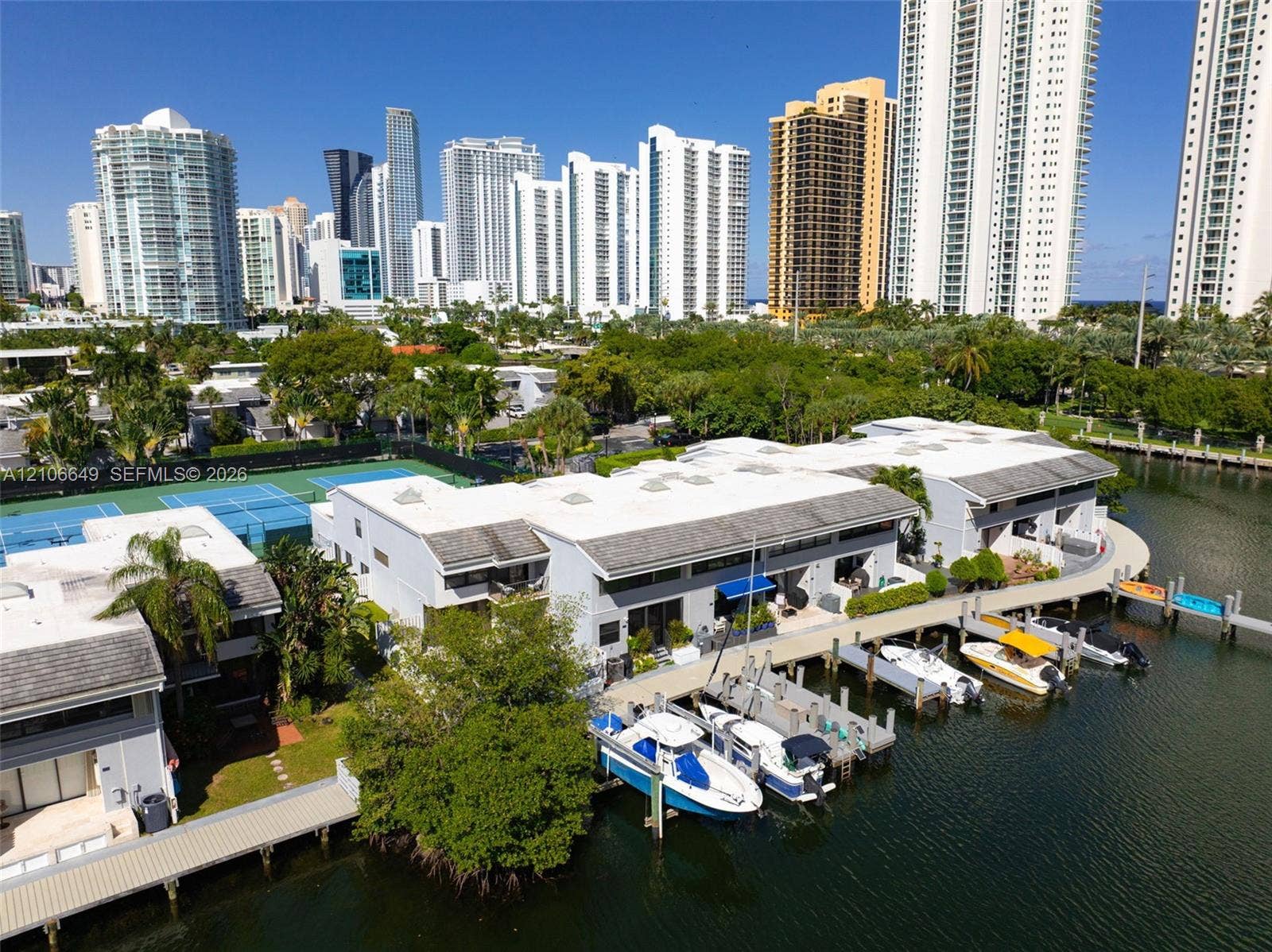 216 Poinciana Drive, #206, Sunny Isles Beach, FL 33160 Waterfront property featuring a private deep-water dock, integrated boat slips, paved pathways, and tennis courts