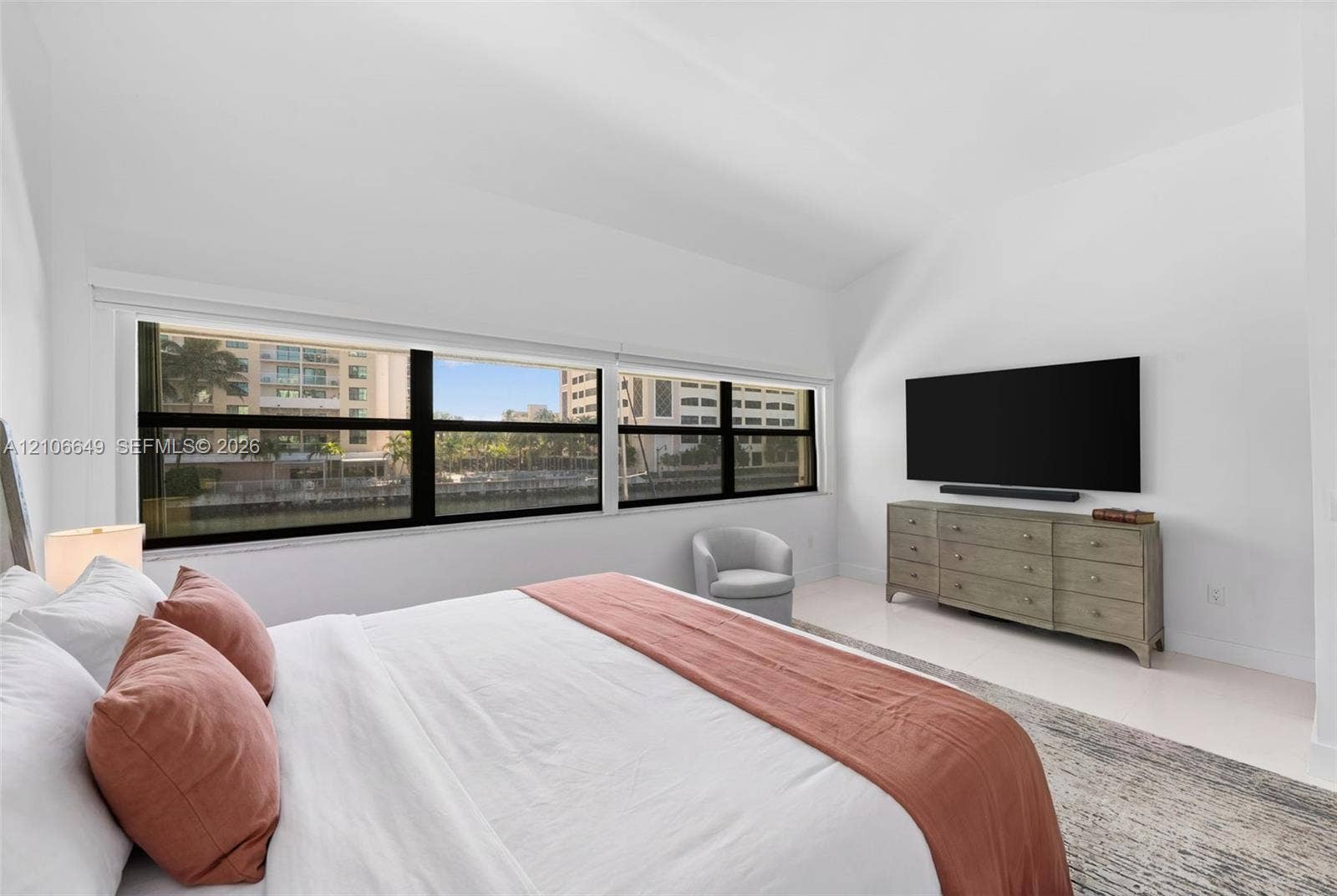 216 Poinciana Drive, #206, Sunny Isles Beach, FL 33160 Vaulted ceiling, expansive windows with black frames, and light-toned flooring