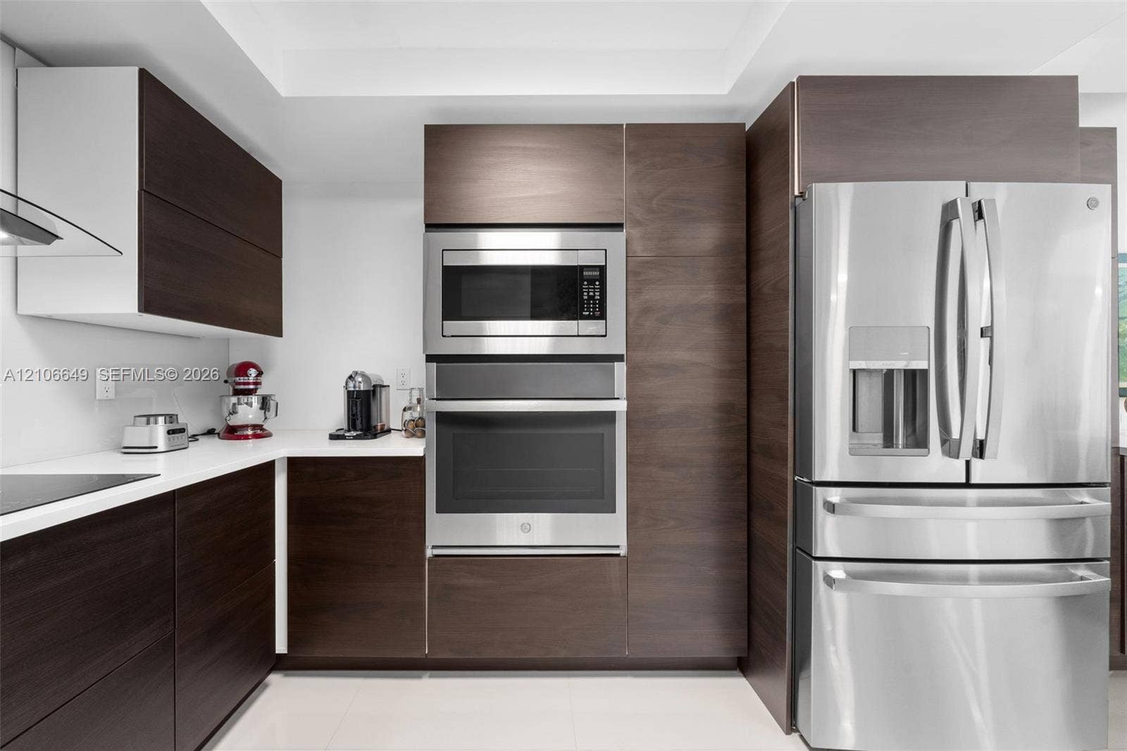 216 Poinciana Drive, #206, Sunny Isles Beach, FL 33160 Modern kitchen featuring dark wood-finish cabinetry, solid surface countertops, stainless steel wall oven, built-in microwave, and stainless steel french-door refrigerator