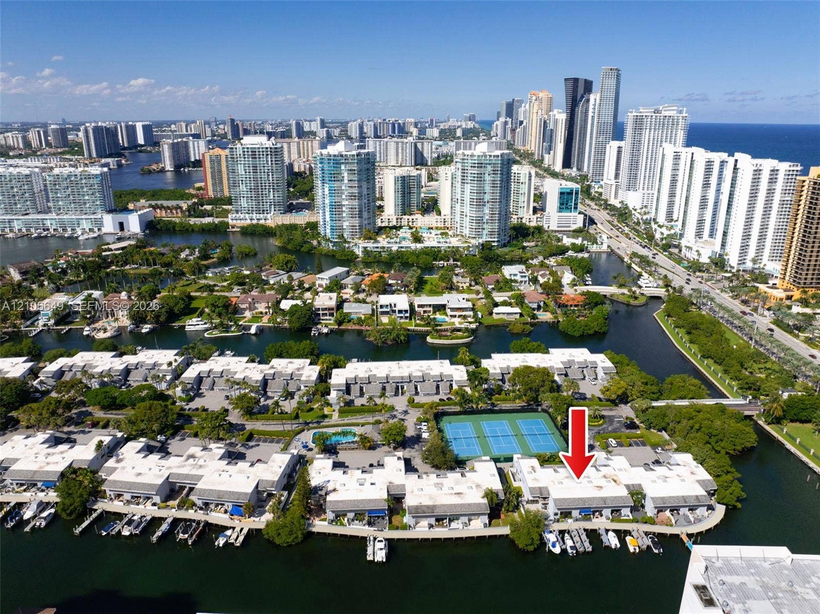 216 Poinciana Drive, #206, Sunny Isles Beach, FL 33160 Aerial perspective featuring waterfront residential property with private boat slips, direct canal access, and communal tennis courts