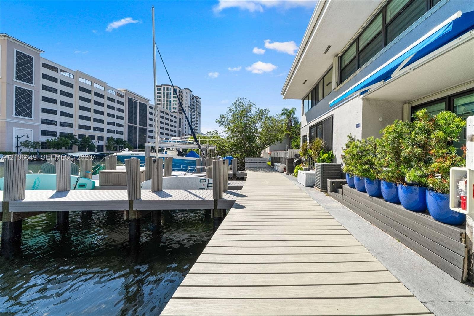 216 Poinciana Drive, #206, Sunny Isles Beach, FL 33160 Waterfront property featuring a private composite dock, direct water access, and exterior stairs with integrated landscaping