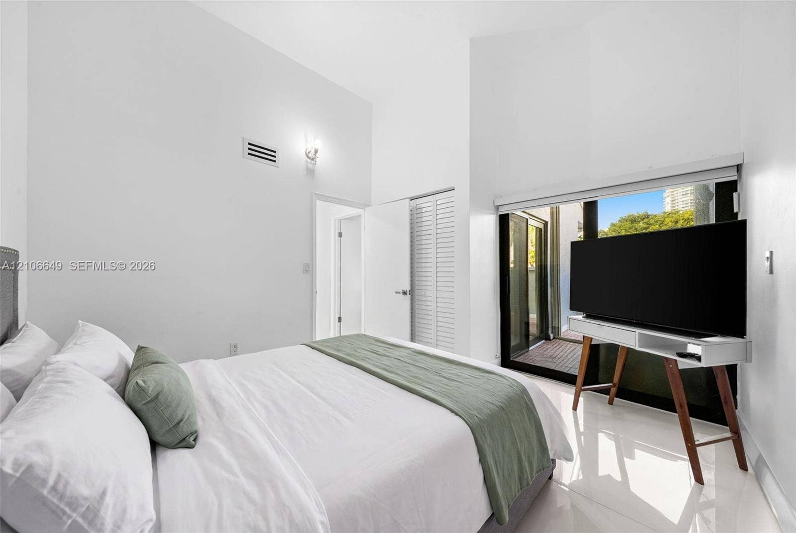 216 Poinciana Drive, #206, Sunny Isles Beach, FL 33160 Vaulted ceilings, large sliding glass doors, white tiled flooring, and louvered closet doors