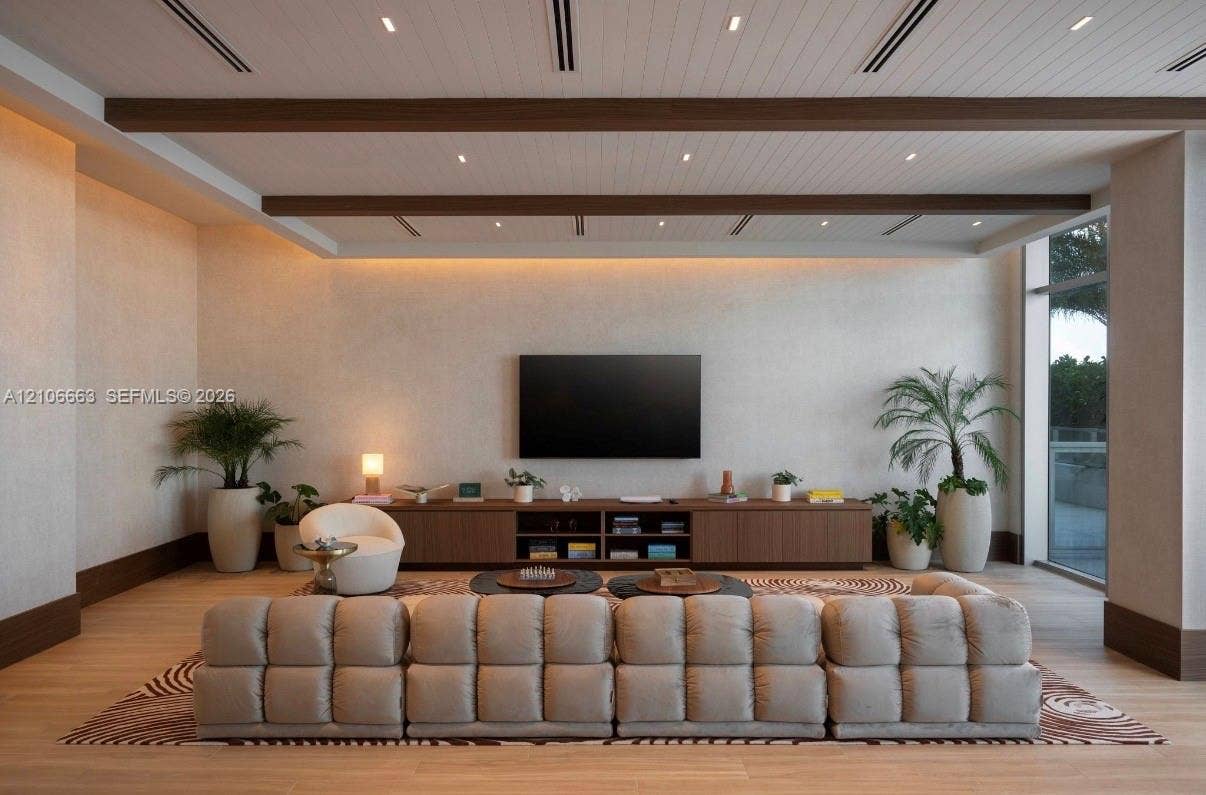 High-ceiling space featuring exposed wood-finish beams, recessed lighting, wood-finish flooring, and built-in low-profile cabinetry