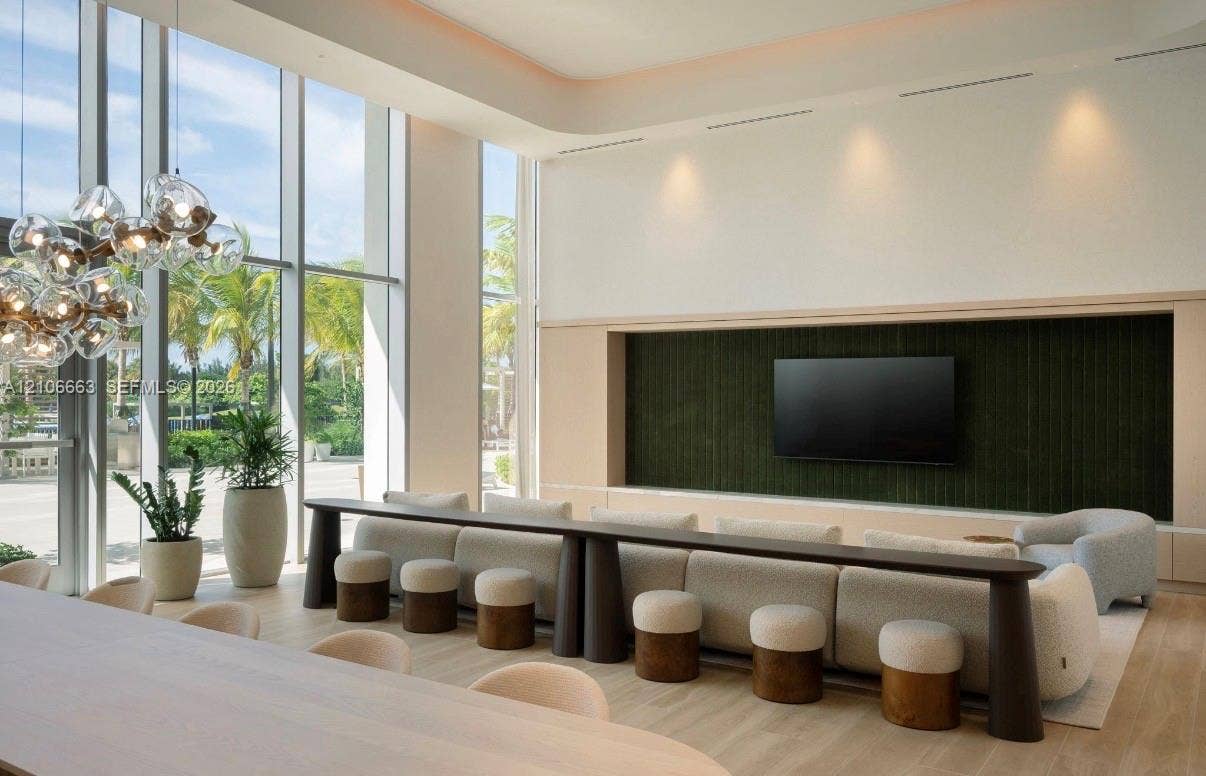 Floor-to-ceiling glass windows, recessed ceiling lighting, wood-finish flooring, integrated wall-paneling, and multi-light spherical chandelier