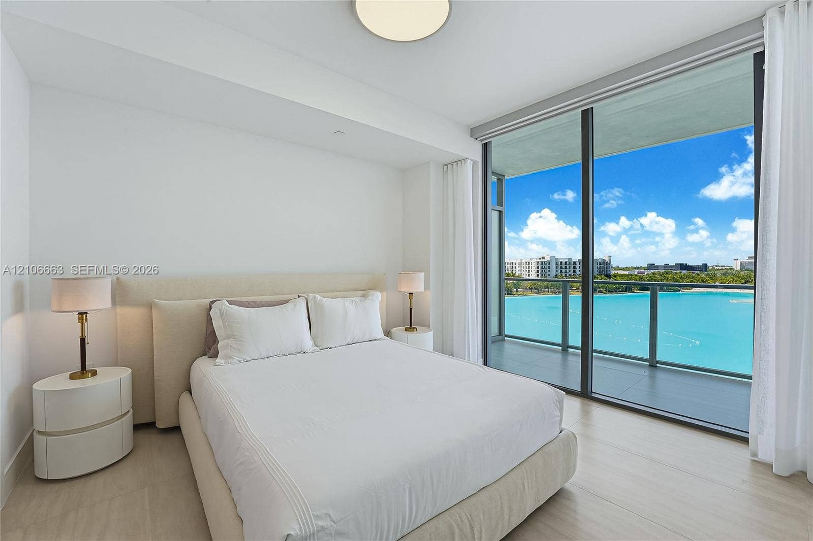 Floor-to-ceiling sliding glass doors, private covered balcony, wood-finish flooring, and neutral wall tones