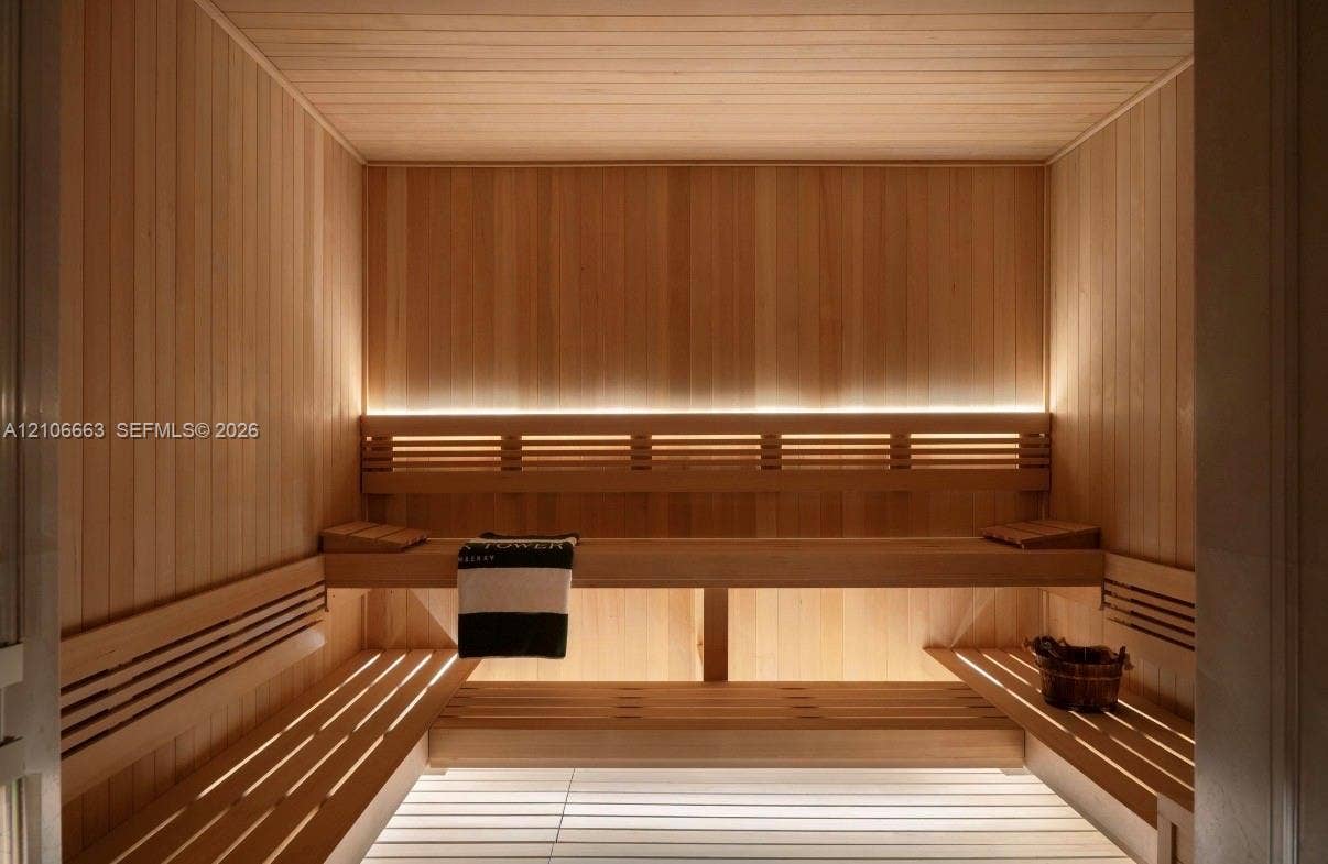 Sauna featuring custom wood wall paneling, tiered wood bench seating, and integrated linear lighting