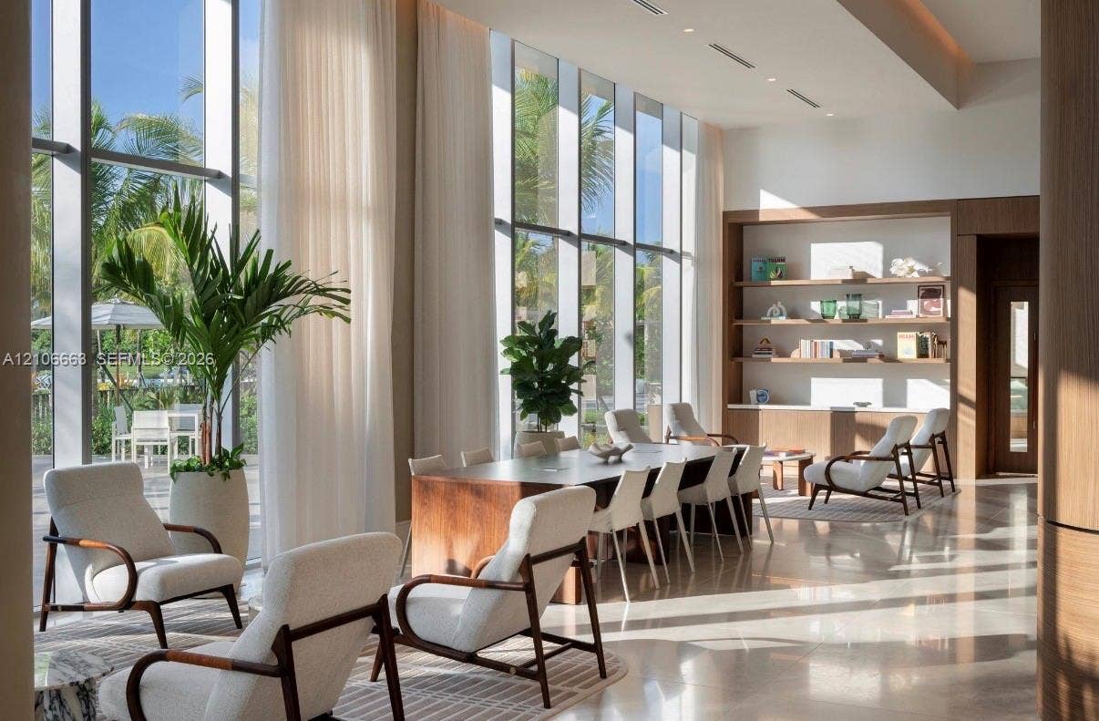 Floor-to-ceiling windows, high coffered ceiling with recessed lighting, polished stone flooring, and custom built-in wood shelving