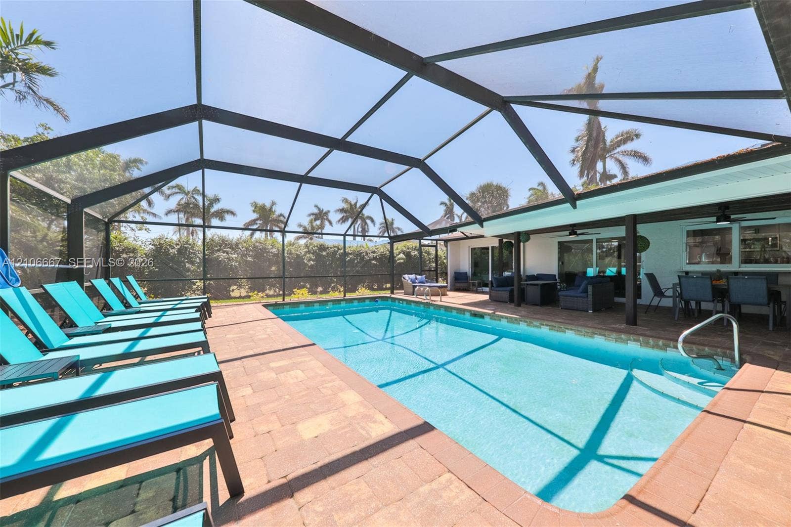 209 Bayshore Drive, Cape Coral, FL 33904 Screen-enclosed swimming pool featuring a paver deck and built-in steps