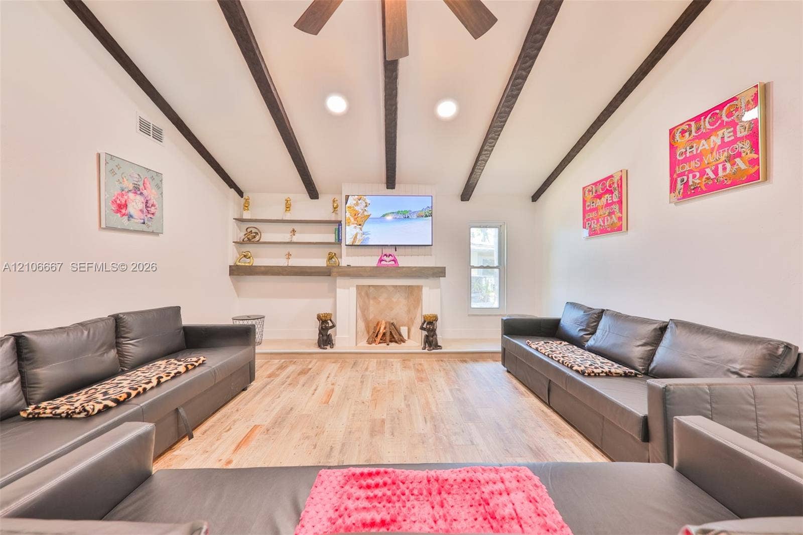 209 Bayshore Drive, Cape Coral, FL 33904 Vaulted ceiling featuring exposed dark wood beams, wood-finish flooring, fireplace with a decorative mantel, and built-in wall shelving