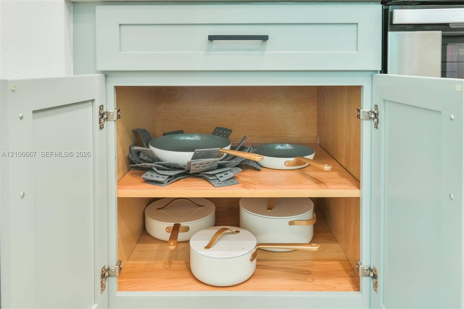 209 Bayshore Drive, Cape Coral, FL 33904 Shaker-style cabinetry with light blue finish, matte black hardware, and natural wood interior shelving