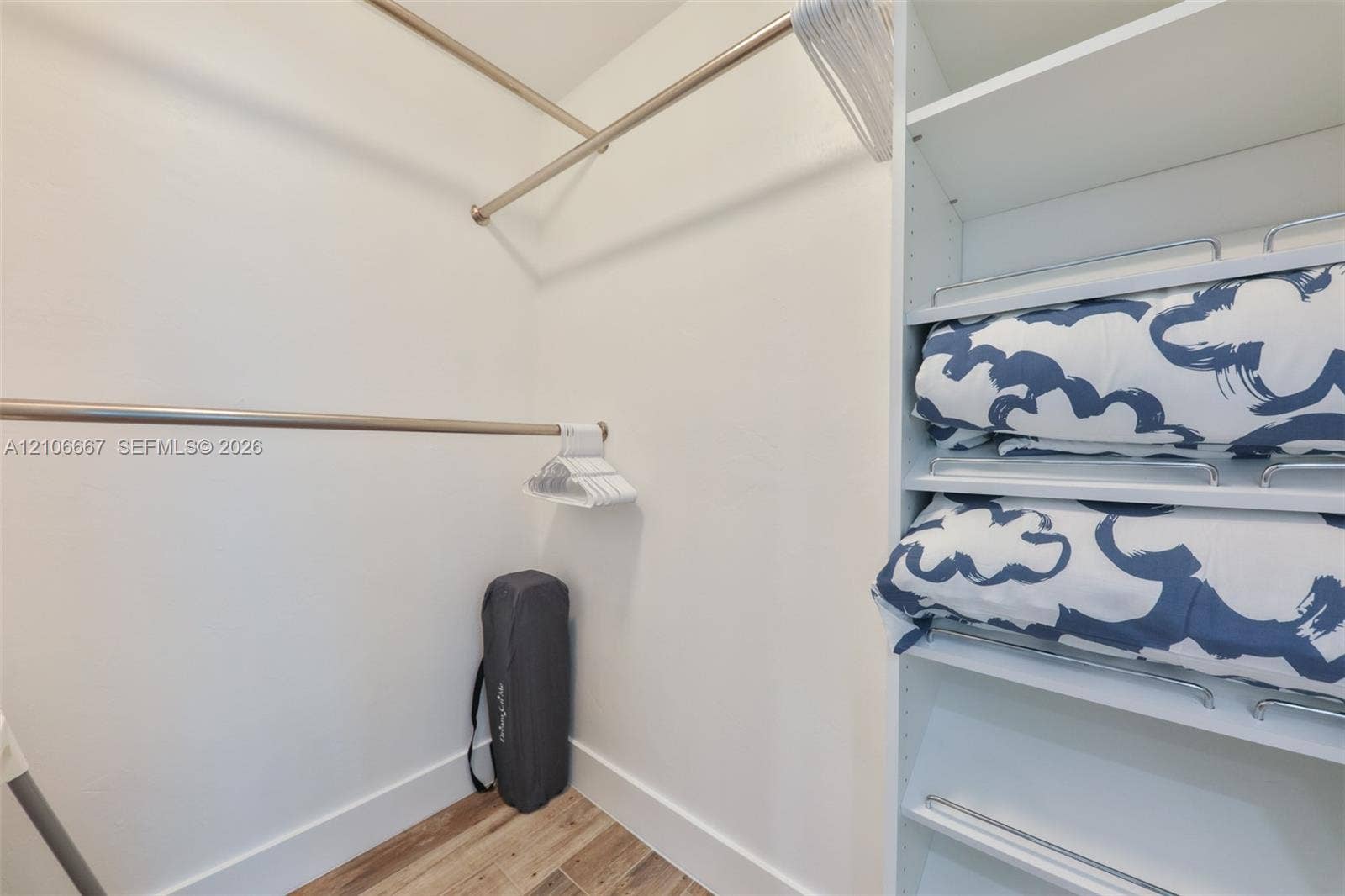209 Bayshore Drive, Cape Coral, FL 33904 Walk-in closet featuring white built-in shelving, adjustable metal clothing rods, and wood-finish flooring