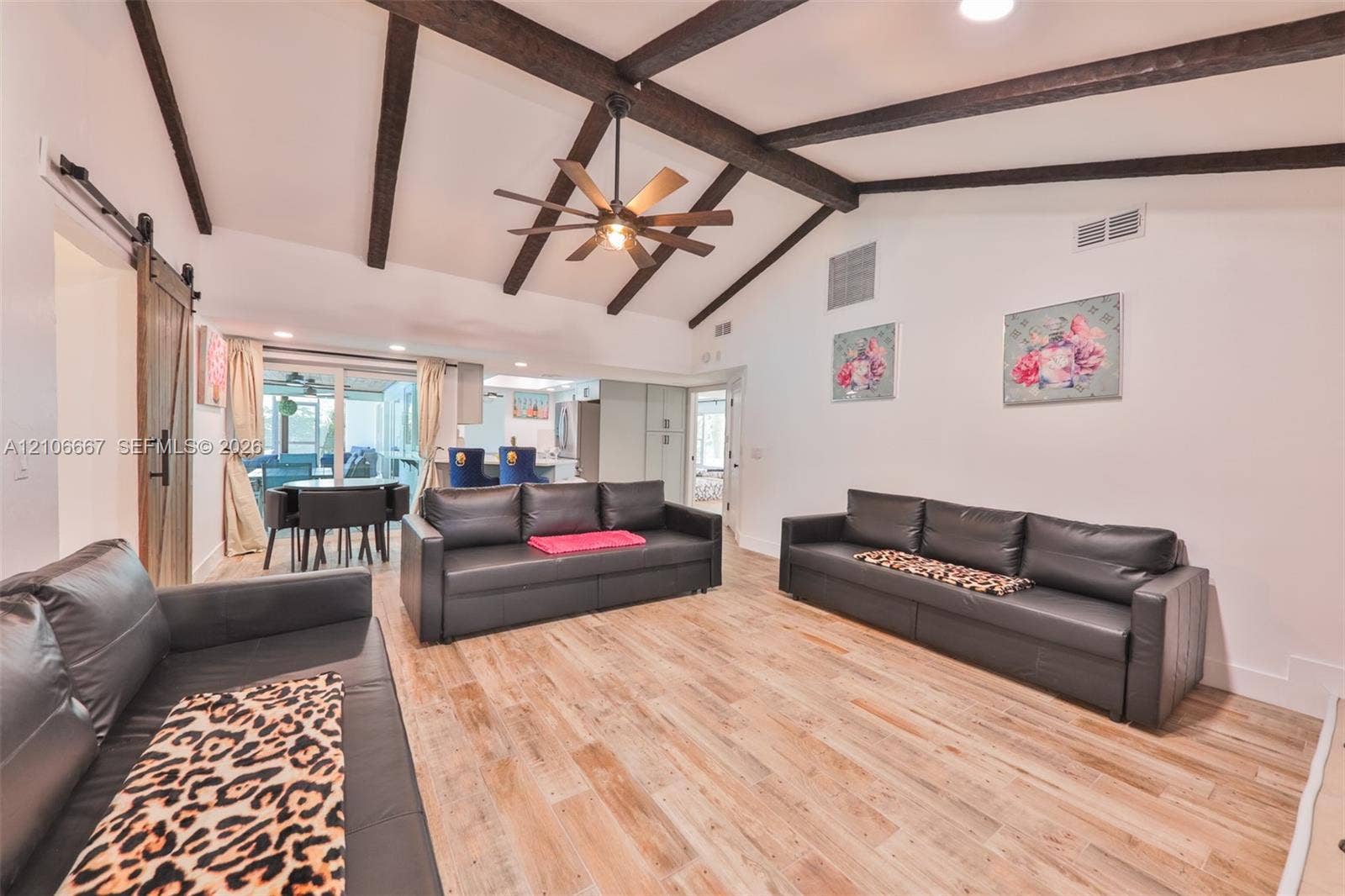 209 Bayshore Drive, Cape Coral, FL 33904 Vaulted ceiling featuring exposed decorative wooden beams, wood-finish flooring, and a central ceiling fan with an integrated light fixture