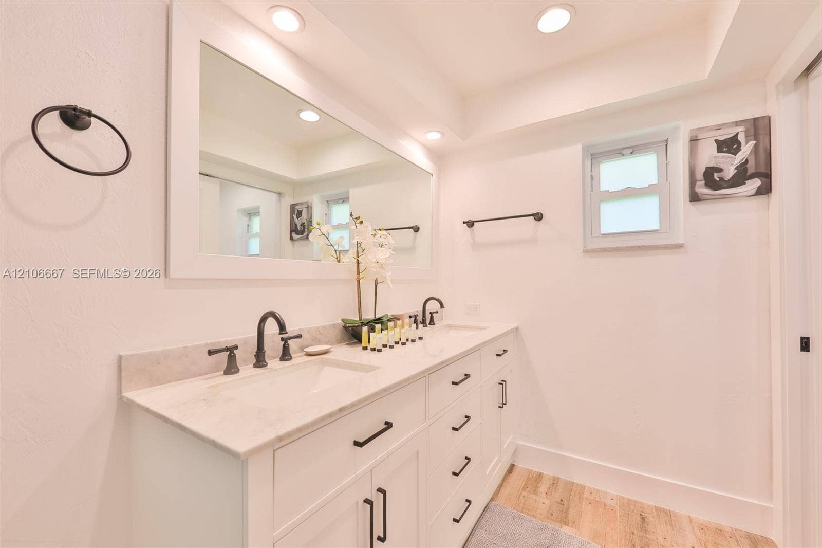 209 Bayshore Drive, Cape Coral, FL 33904 Dual-sink vanity with stone countertop, matte black hardware, integrated cabinetry, wood-finish flooring, and recessed ceiling lighting