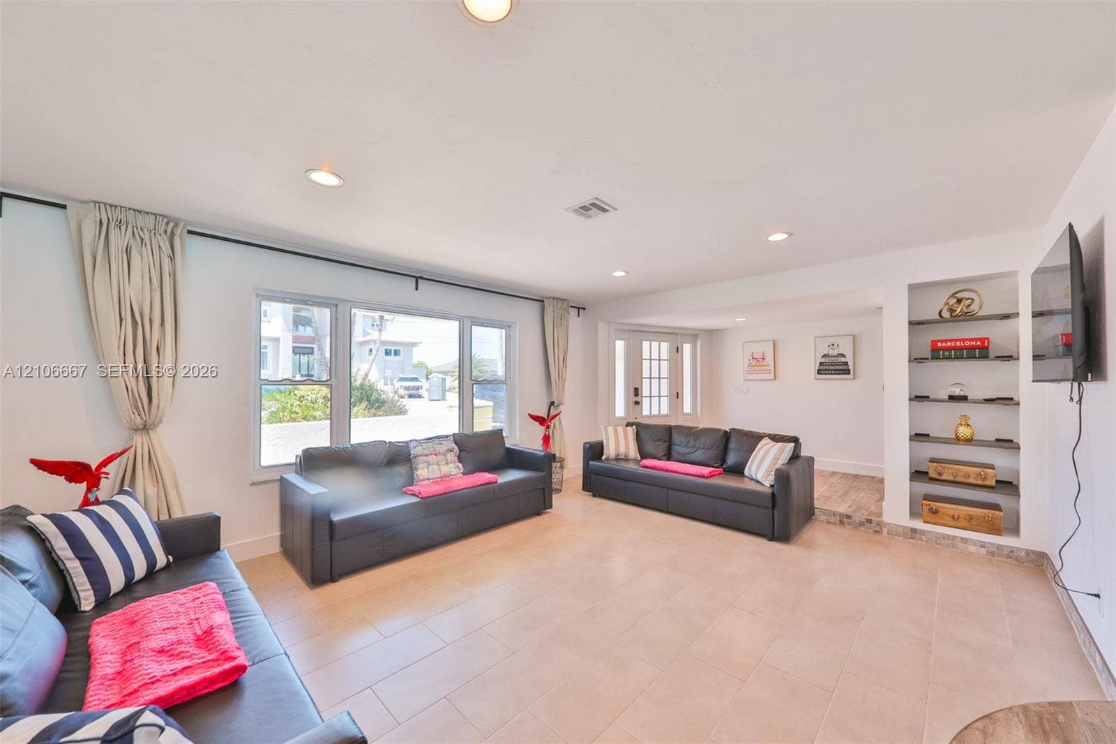 209 Bayshore Drive, Cape Coral, FL 33904 Open-concept living space featuring large multi-pane windows, recessed ceiling lighting, ceramic tile flooring, and a built-in recessed shelving unit