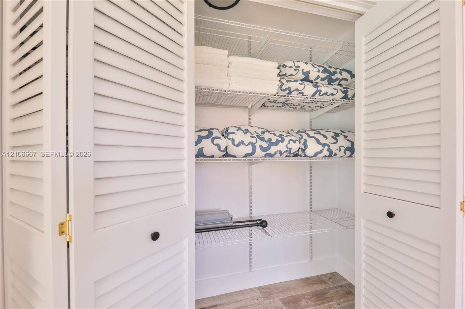 209 Bayshore Drive, Cape Coral, FL 33904 Storage closet featuring white louvered bifold doors, adjustable wire shelving, and wood-finish tile flooring