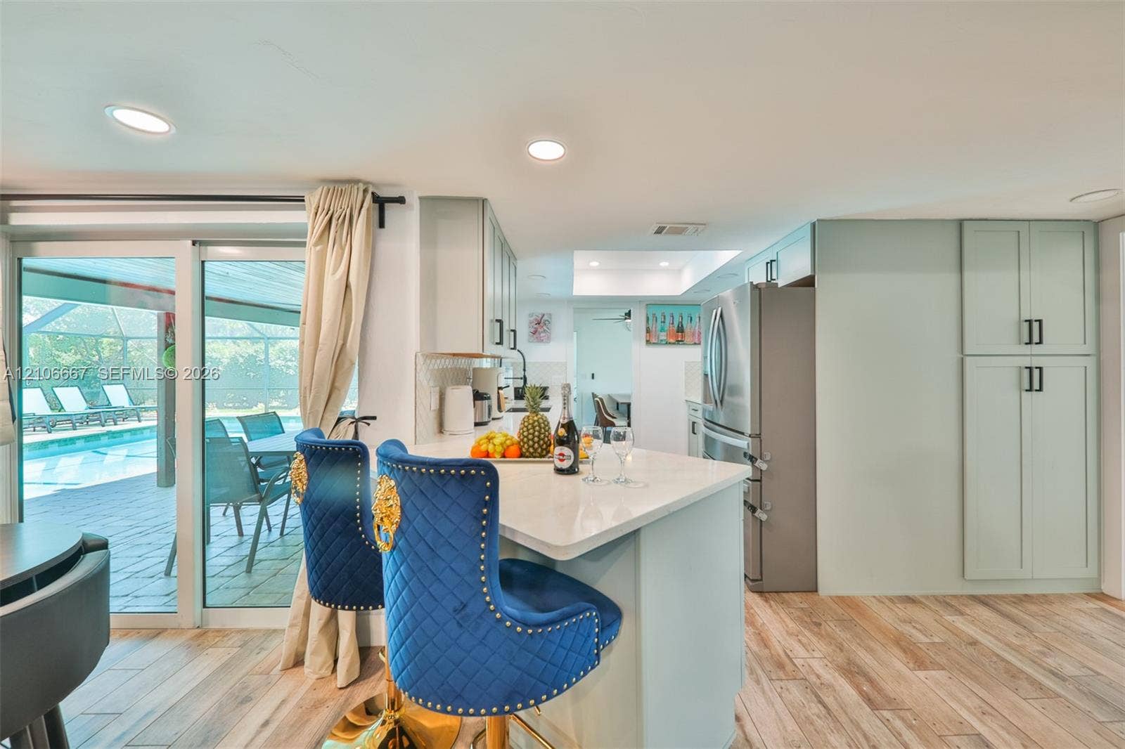 209 Bayshore Drive, Cape Coral, FL 33904 Kitchen featuring a quartz-topped island, light-toned cabinetry, stainless steel refrigerator, recessed lighting, and wood-finish flooring