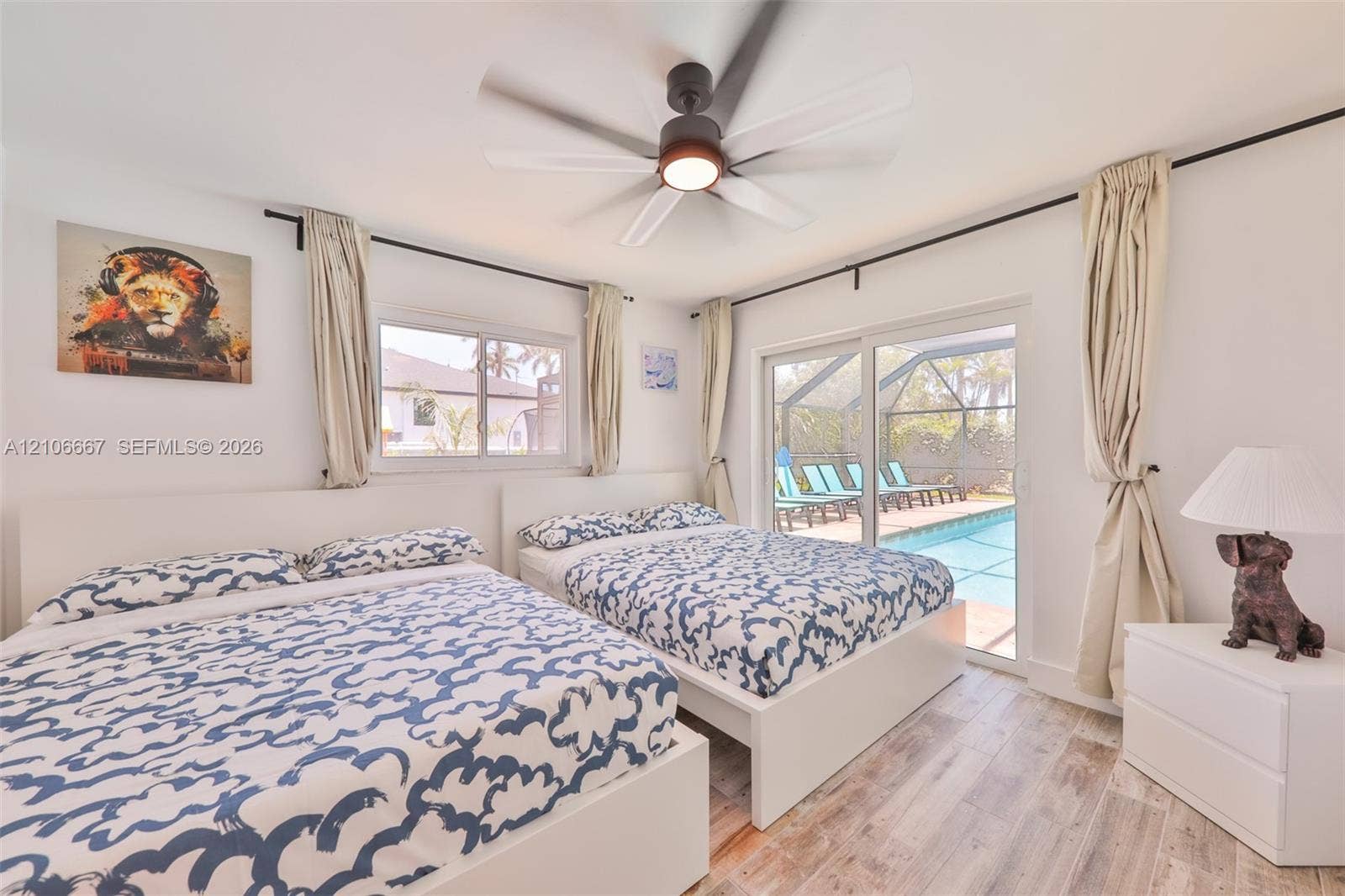 209 Bayshore Drive, Cape Coral, FL 33904 Room featuring wood-finish flooring, a multi-blade ceiling fan with integrated lighting, and sliding glass doors providing access to a screened-in pool enclosure