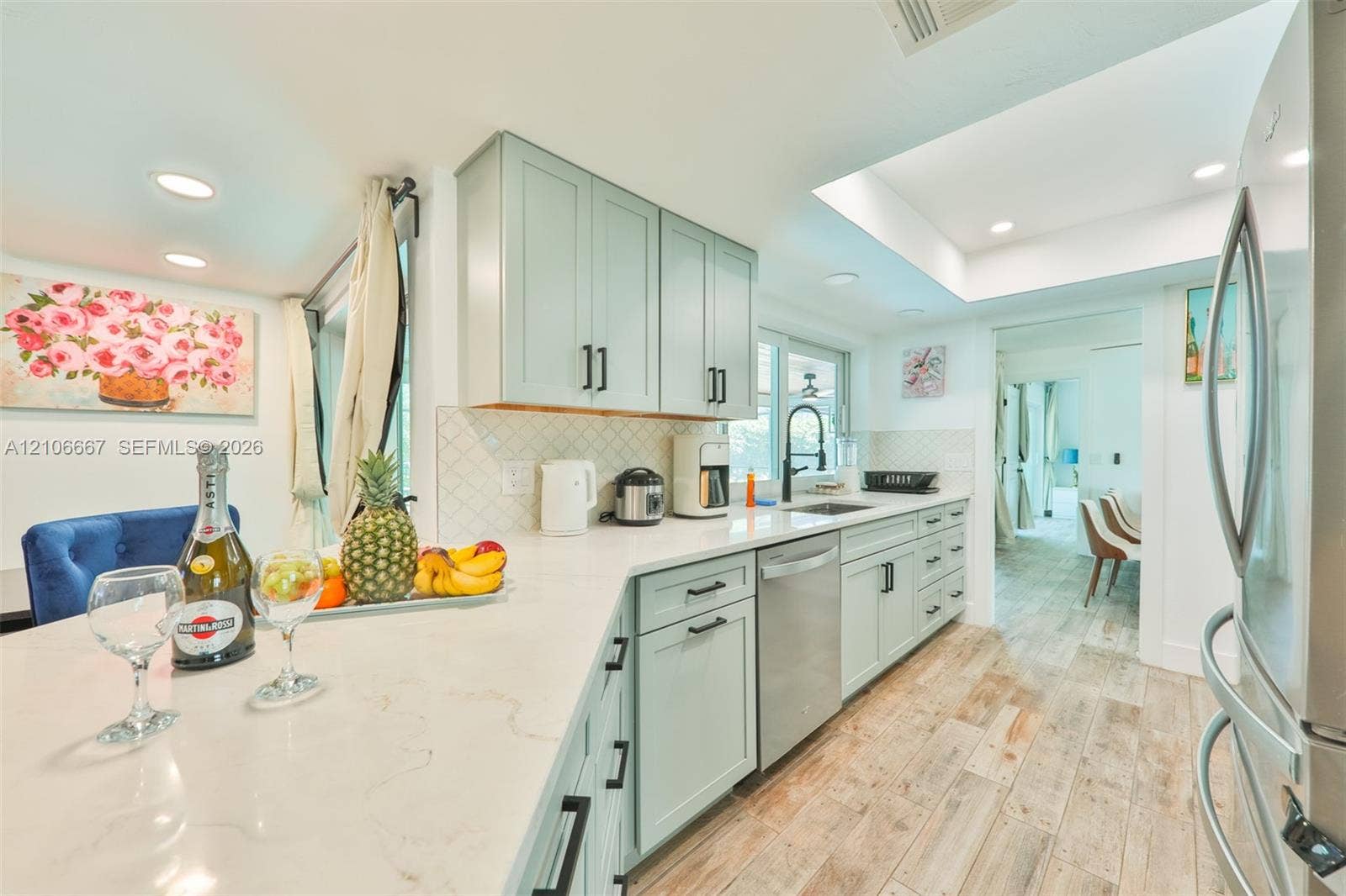 209 Bayshore Drive, Cape Coral, FL 33904 Kitchen featuring custom cabinetry, stone-finish countertops, stainless steel appliances, a recessed tray ceiling, and wood-finish flooring