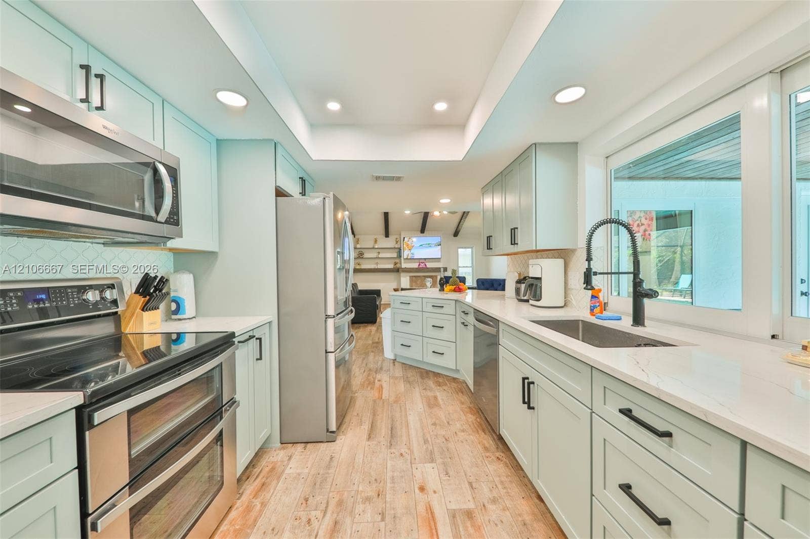 209 Bayshore Drive, Cape Coral, FL 33904 Kitchen featuring light-toned cabinetry, stainless steel appliances, quartz countertops, wood-finish flooring, and recessed lighting