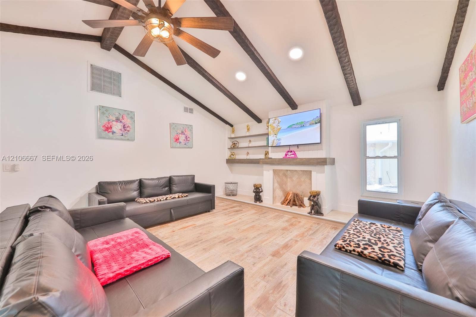 209 Bayshore Drive, Cape Coral, FL 33904 Vaulted ceiling with exposed decorative beams, wood-finish flooring, fireplace with a mantel, and built-in wall shelving