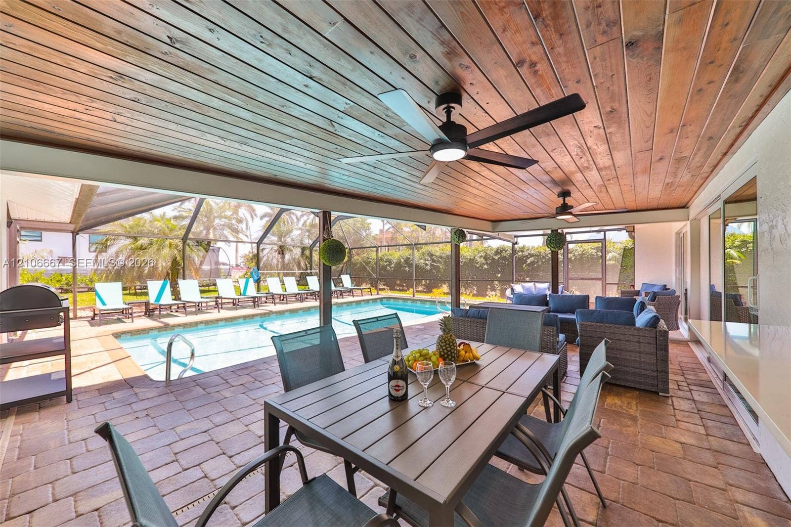 209 Bayshore Drive, Cape Coral, FL 33904 Covered lanai featuring a wood-plank ceiling, recessed lighting, dual ceiling fans, paver flooring, and a screened-in swimming pool