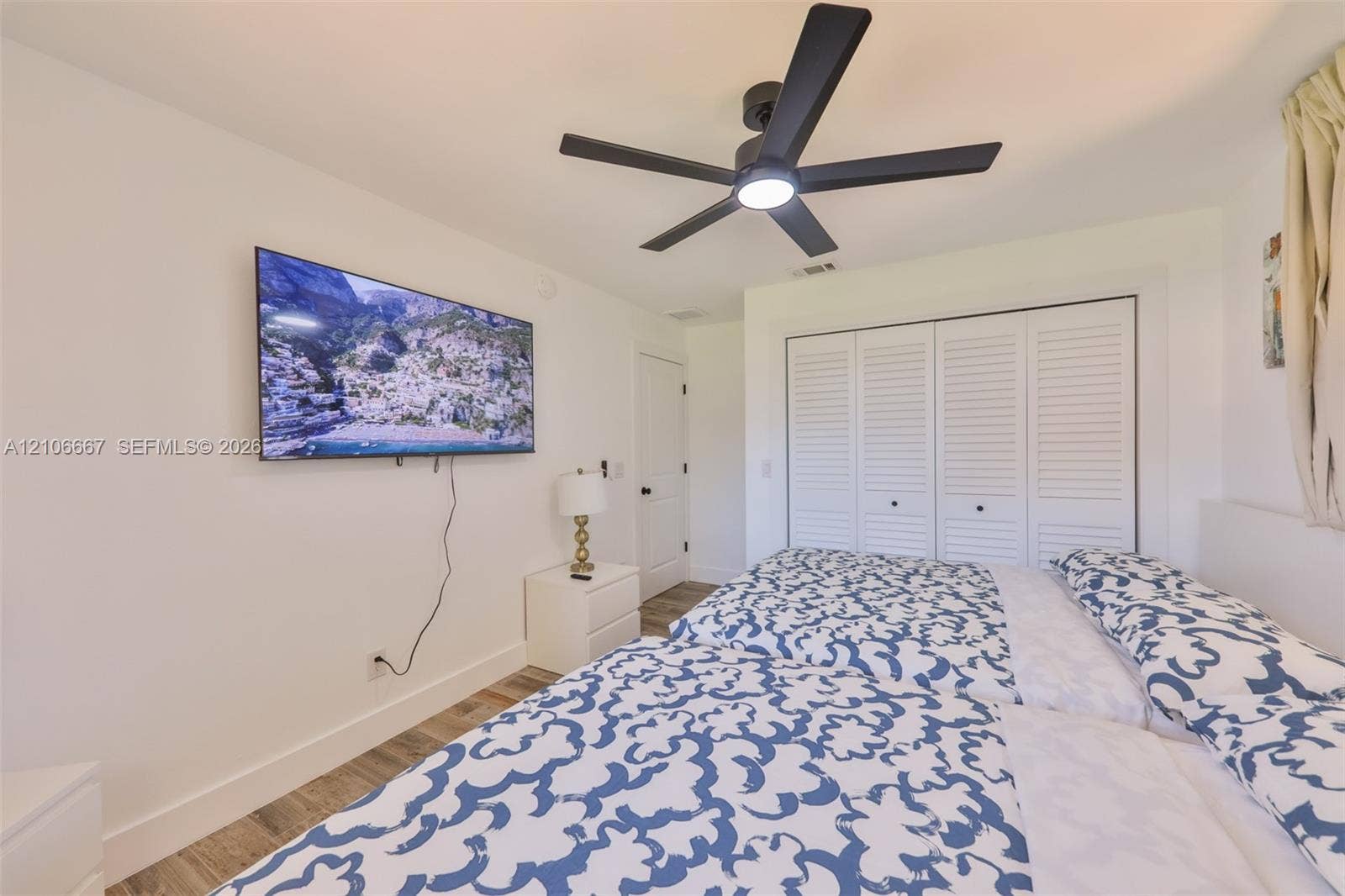 209 Bayshore Drive, Cape Coral, FL 33904 Wood-finish flooring, multi-blade ceiling fan with integrated lighting, and white bi-fold closet doors