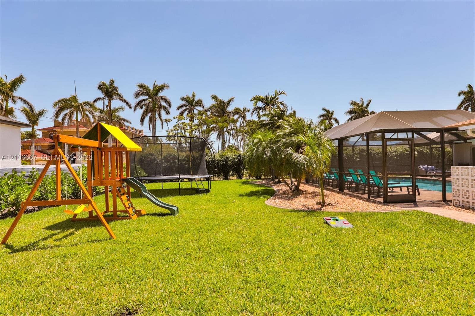 209 Bayshore Drive, Cape Coral, FL 33904 Outdoor living area featuring a screened-in swimming pool, manicured lawn, palm trees, and structural hardscaping