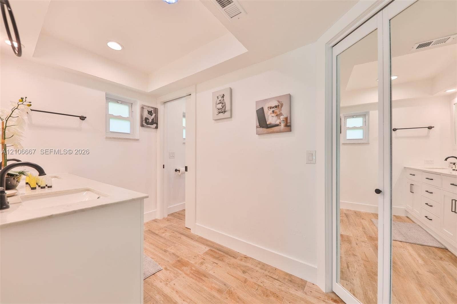 209 Bayshore Drive, Cape Coral, FL 33904 Bathroom featuring white cabinetry, stone-surface countertops, wood-finish flooring, recessed lighting, and a full-length mirrored closet door
